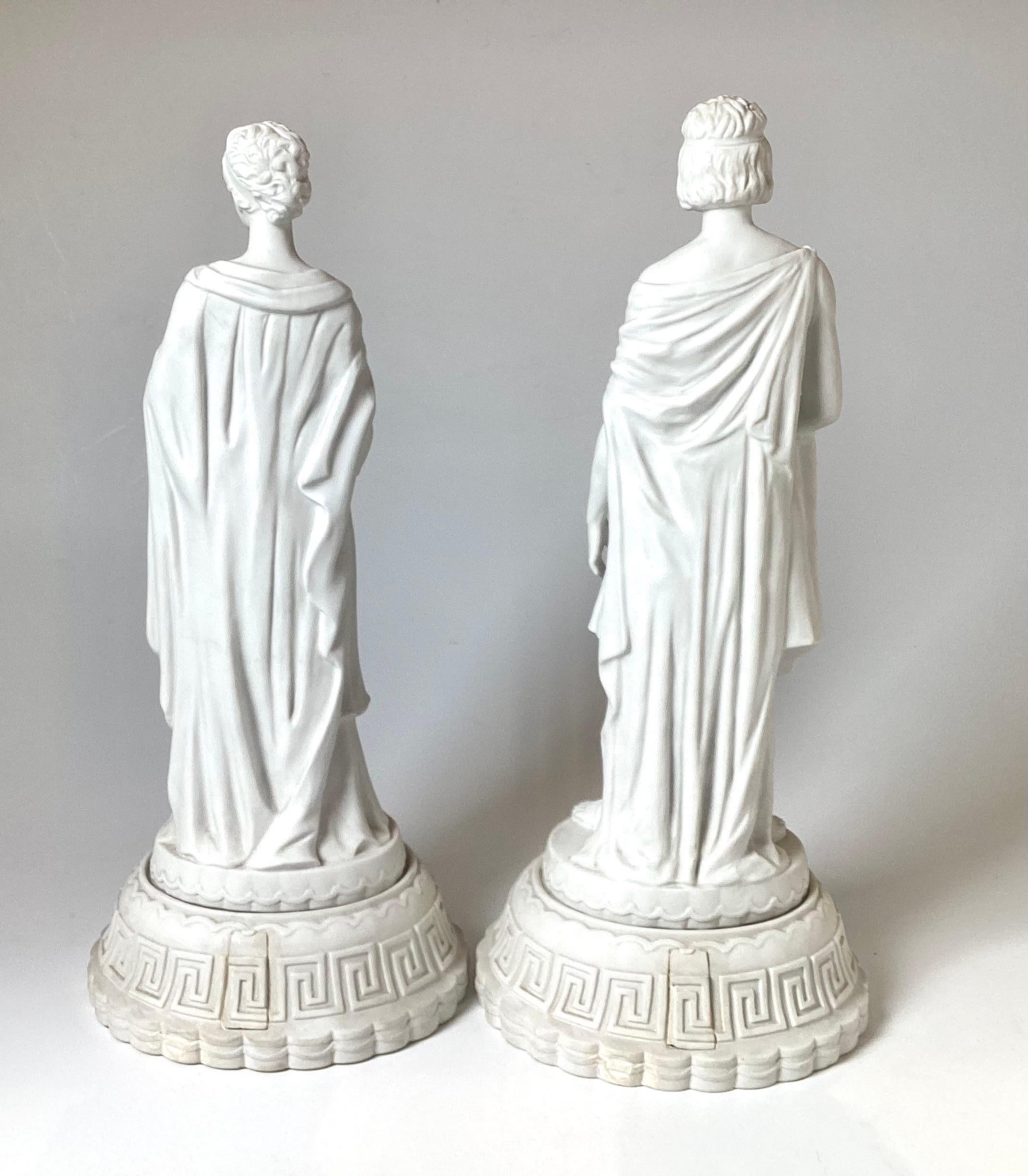 A Pair of Parian porcelain bisque neoclassical statues of a Greek couple. The original pair in white bisque finish with Greek key decoration at the bases, European, possibly Italian, 17 inches tall