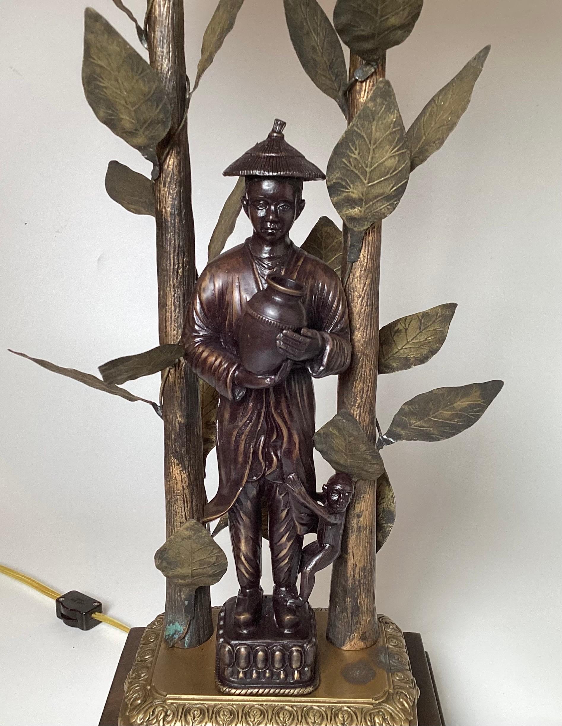 A pair of whimsical Chinoiserie style patinated lamps by Frederick Cooper. The bamboo motif sides with bamboo leaves with an Asian man carrying a water jug. The bronze is two tone which sets off the beautiful design.
