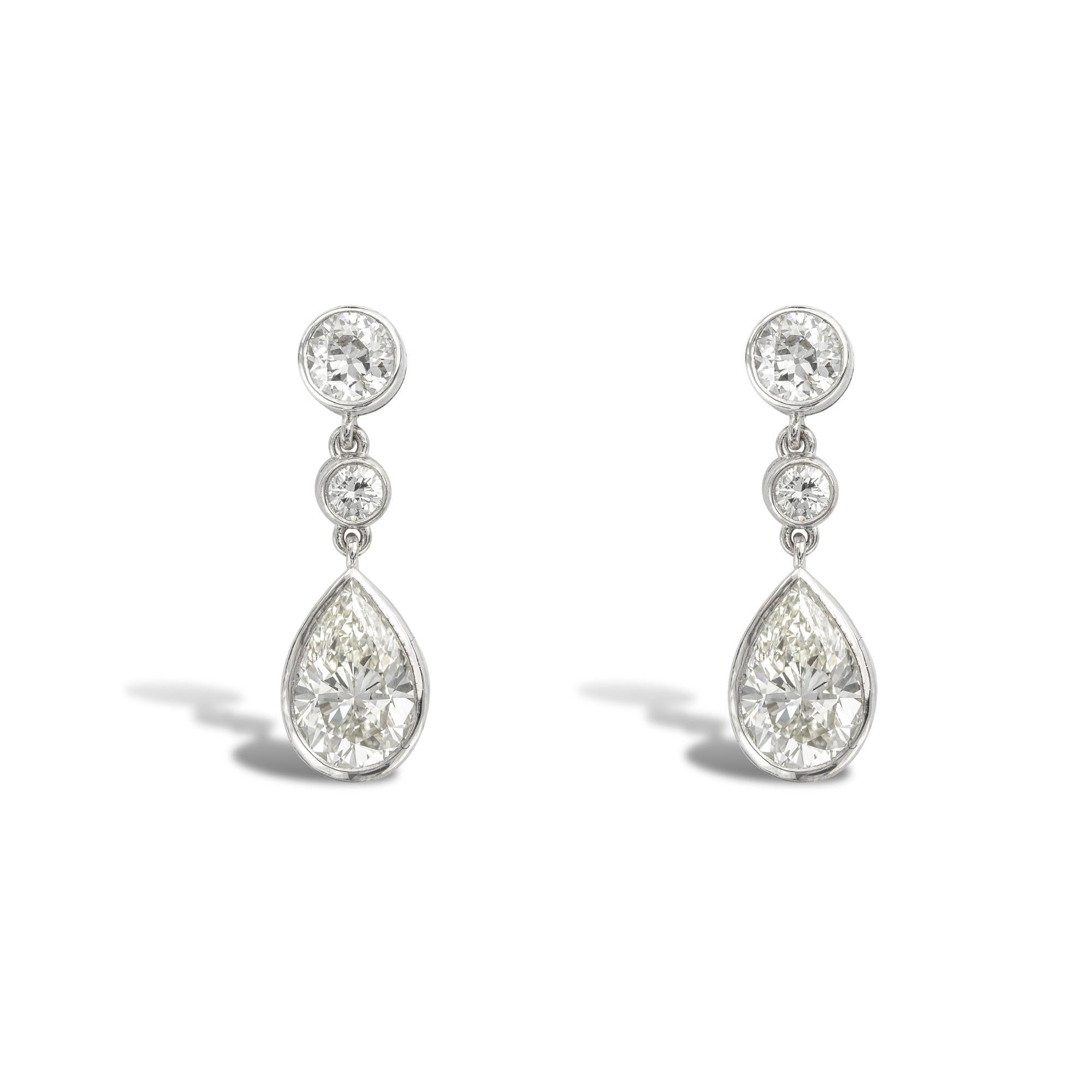 A pair of pear shape diamond drop earrings, the pear shape diamonds weighing 1.02 carats and 1.12 carats, accompanied by GIA reports, stating the diamonds to be of J colour and VS2 clarity, each suspended from two graduating round brilliant-cut