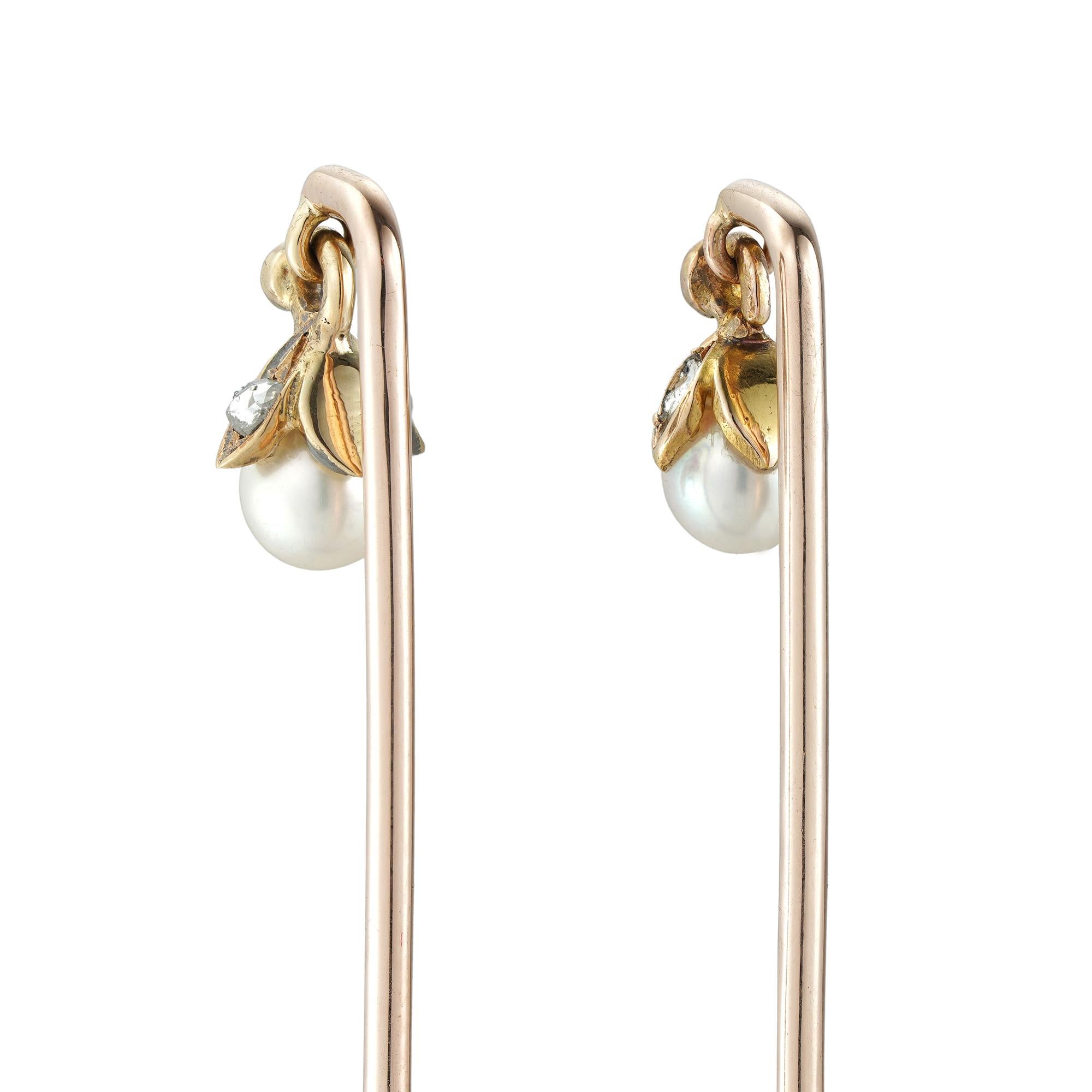 A pair of pearl and diamond stick pins, each pearl set on a rose-cut diamond-set cap, suspended by a diamond-set loop, all set in yellow gold, circa 1890, the jewelled parts measuring 1 x 0.7cm each, the pins measuring 7cm long,  gross weight 4.3