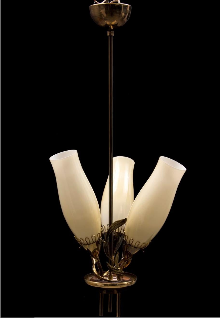 A  lampadario disegnato da Mauri Almari per Idman Oy, modello 51122. Finlandia, circa anni '1950.
In evidenza sul catalogo Idman n. 132, pagina 7.
Ottone lucido con tre paralumi in vetro originali. Misura: H. H. 27,5