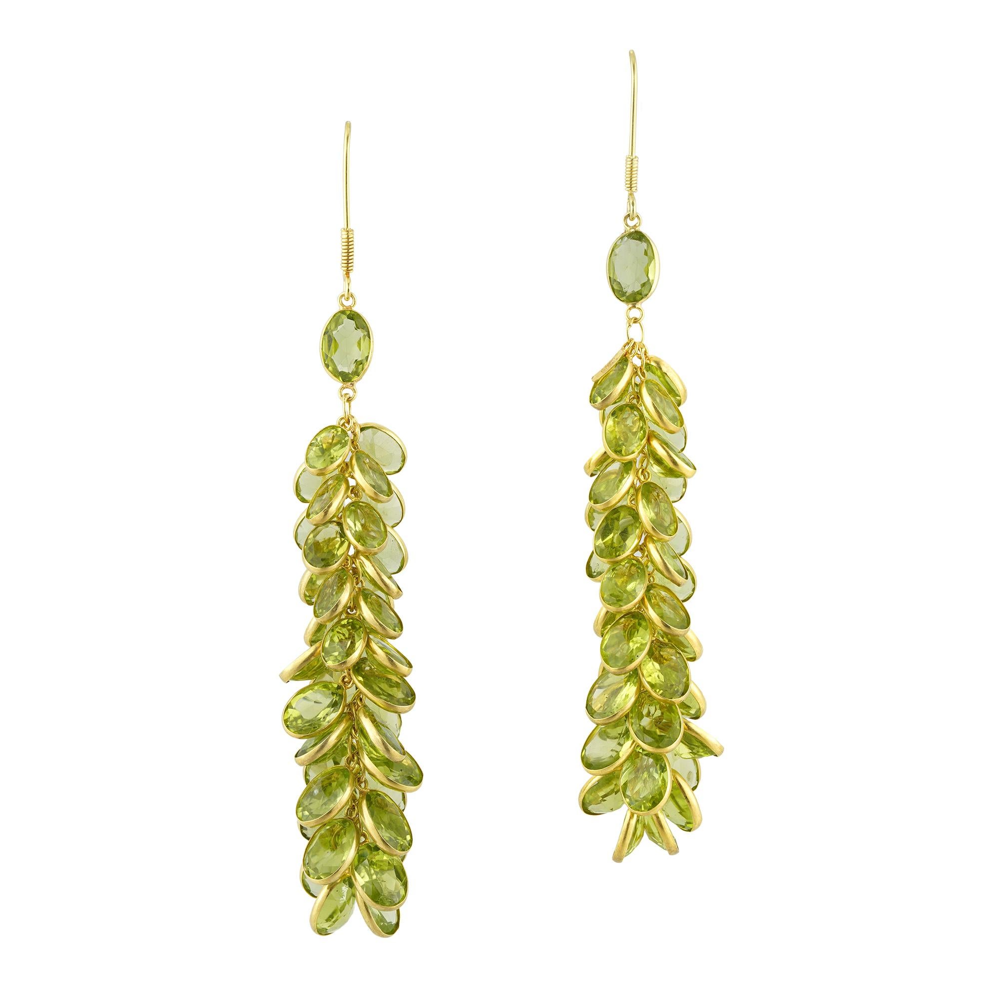 Peridot cascade earrings, each oval mixed cut gemstone spectacle set, with yellow gold and linked with chain, stamped as 14ct, bearing the Bentley and Skinner sponsors mark, measuring 57mmx15mm, weighing 5.7g and 6.5g each.

This pair of earrings is