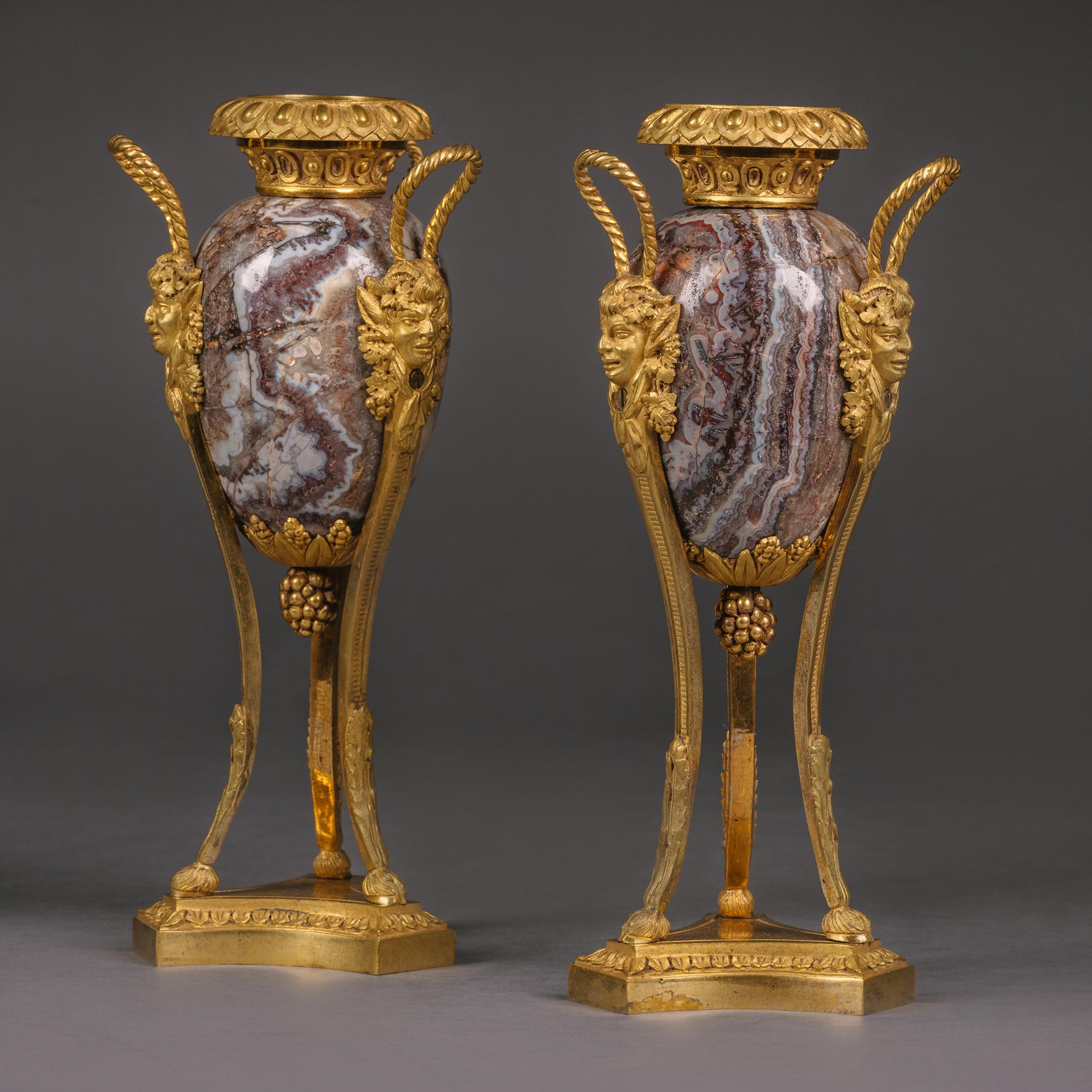 A pair of petite Louis XVI style gilt-bronze mounted fluorspar cassolettes. 

Each cassolette having an ovoid form fluorspar body surmounted by a gilt-bronze stiff-leaf cast neck, a berried terminal, and gilt-bronze Bacchic mask and looped