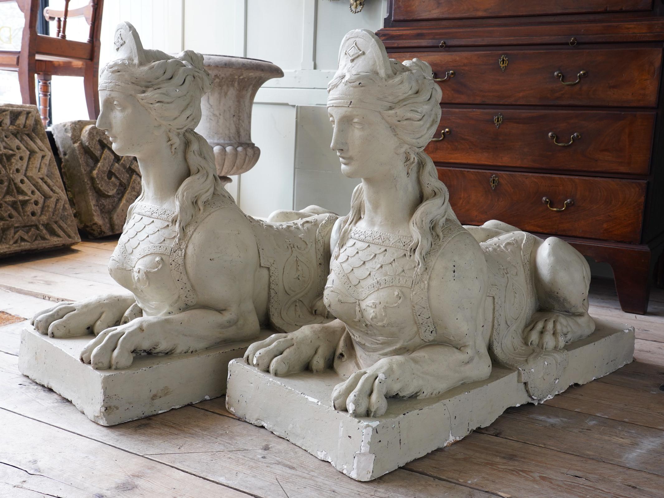 Pair of painted plaster Coade sphinxes.

Each with its hair tied in a chignon, a crescent to the front, with an elaborate saddle-cloth draped over its back, on rectangular bases, both bearing the COADE LAMBETH impressed mark to the