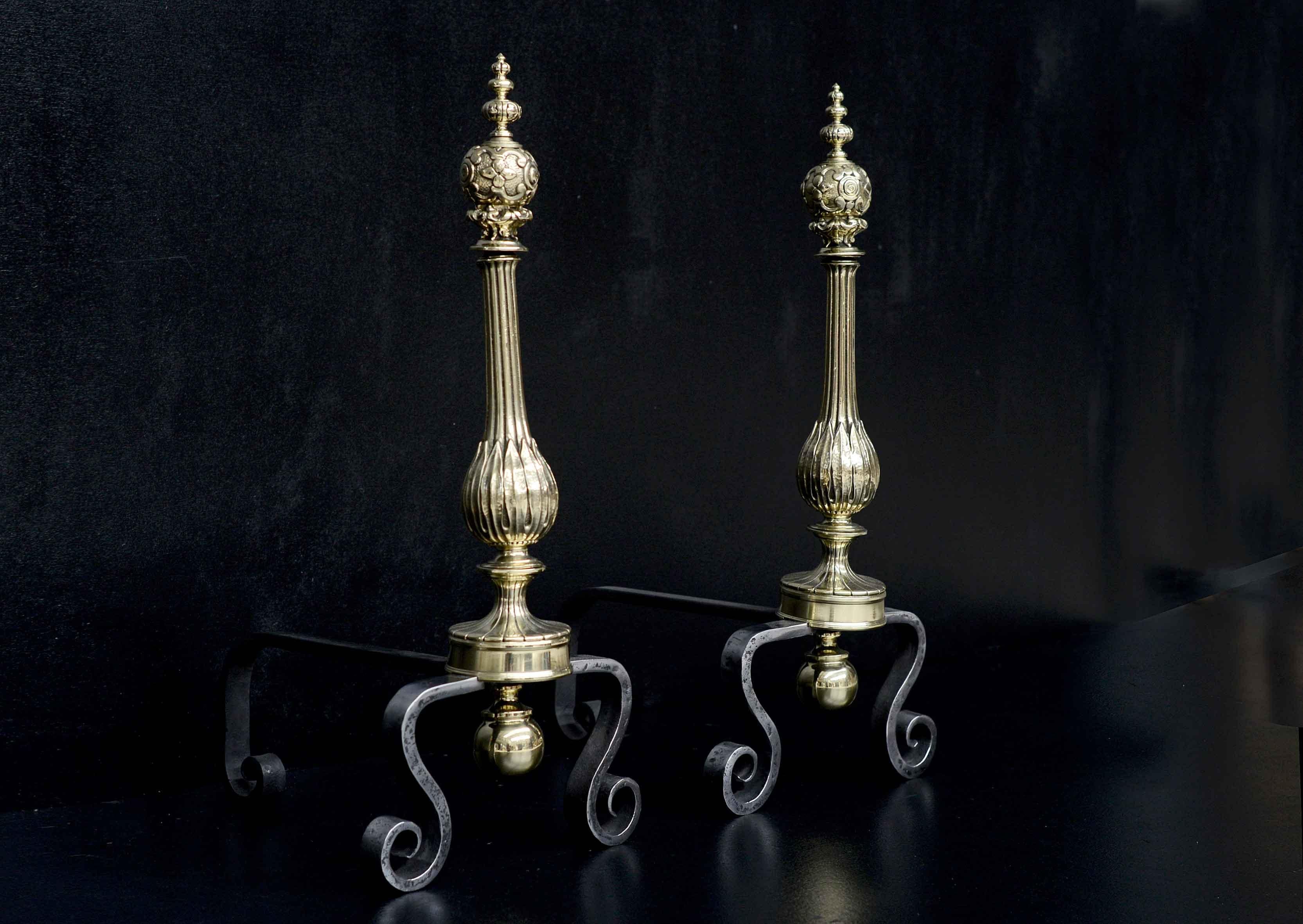 A pair of polished brass firedogs. The shaped shafts surmounted by cast tops and gadrooned finials. The scrolled feet in polished wrought iron. 19th century.

Measures: Height: 570 mm 22 ½