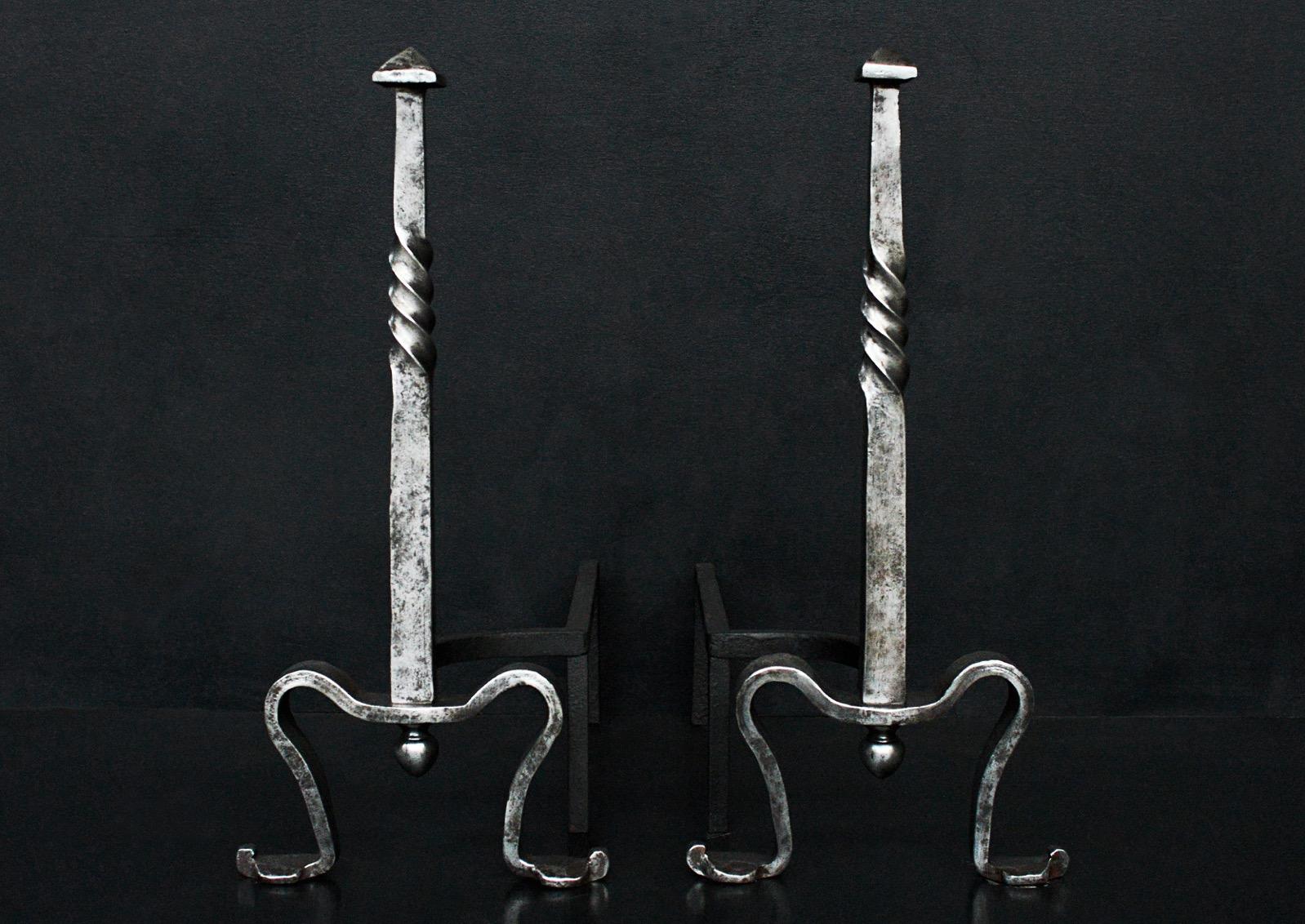 A pair on polished steel firedogs. The shaped feet surmounted by tapered square shaft with barley twist and pyramid finials. English, circa 1900.

Height:	620 mm      	24 ⅜