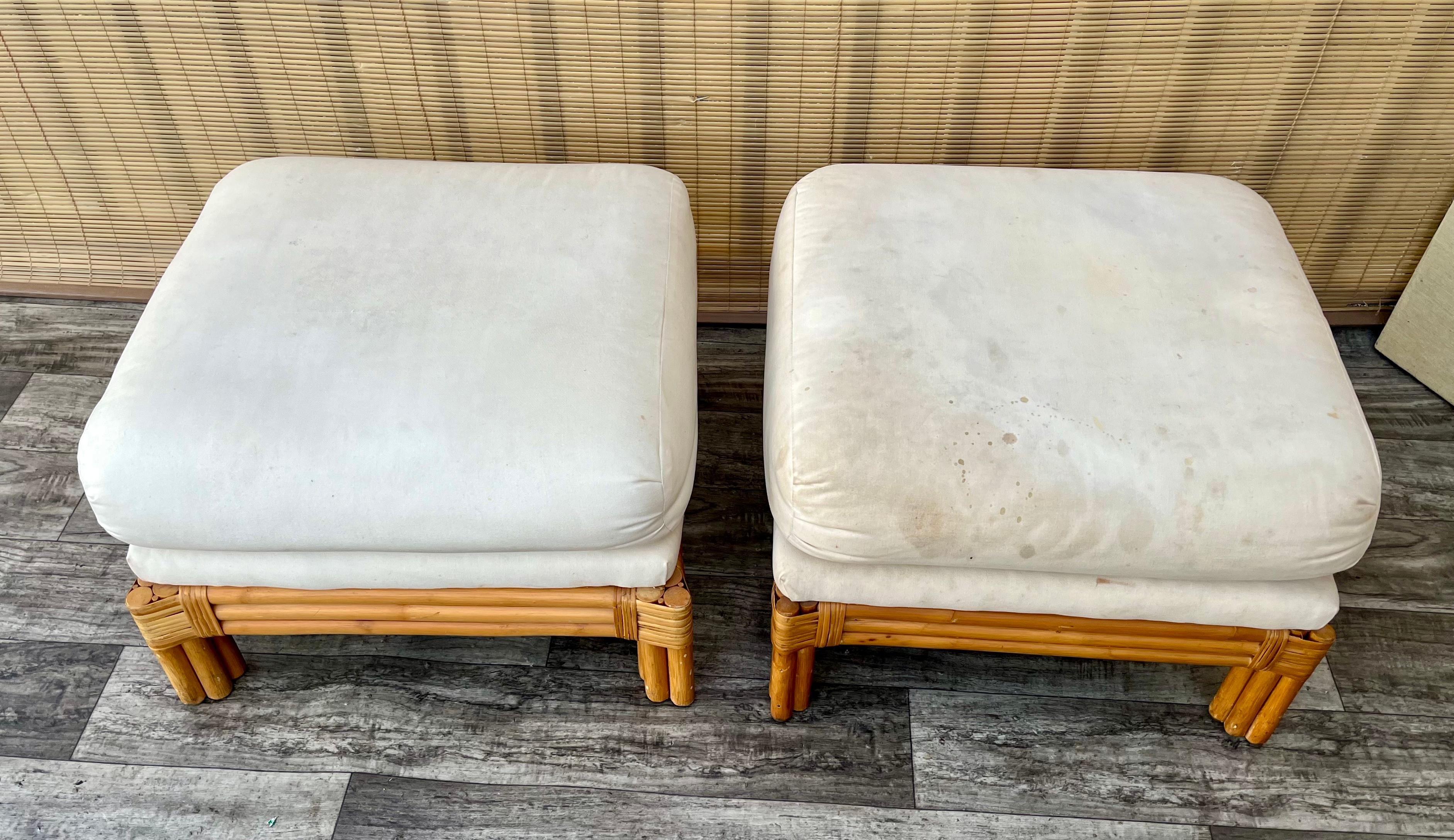 Paire d'ottomans/pouf en rotin vintage Polo Ralph Lauren de style côtier. Circa 1980
Les cadres en rotin sont élégants mais simples et les sièges à double coussin sont recouverts du revêtement blanc cassé d'origine. . 
En bon état d'origine avec des