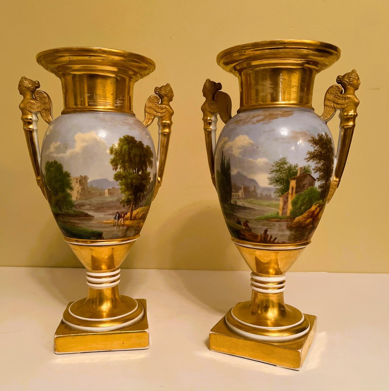This is an exceptional pair of Old Paris vases with beautiful hand-painted panorama scenes. The bucolic scenes are of fashionably dressed people hanging out with cows by a meandering streams with medieval ruins in the background. The clouds and the