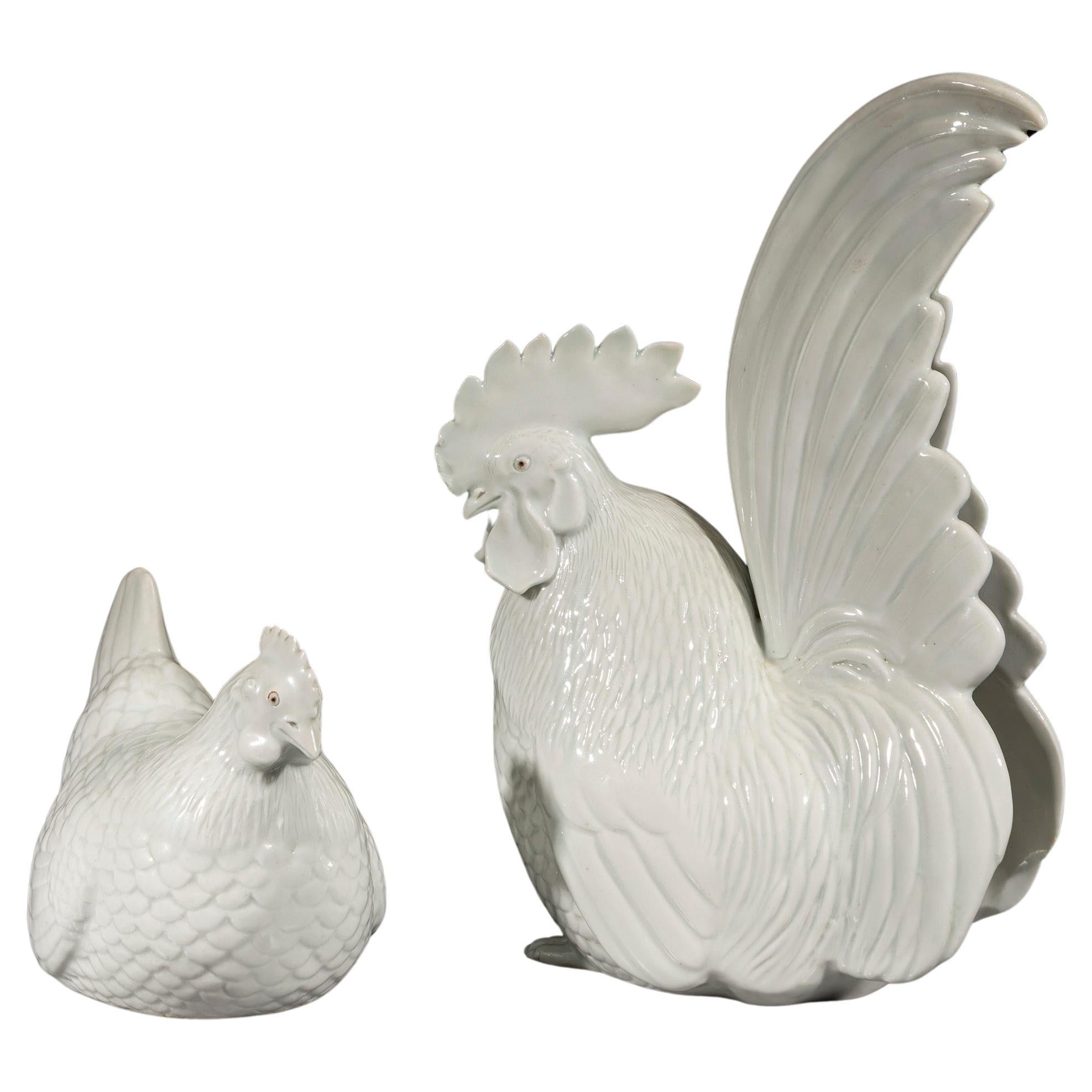 A pair of porcelain okimono depicting a rooster and a hen