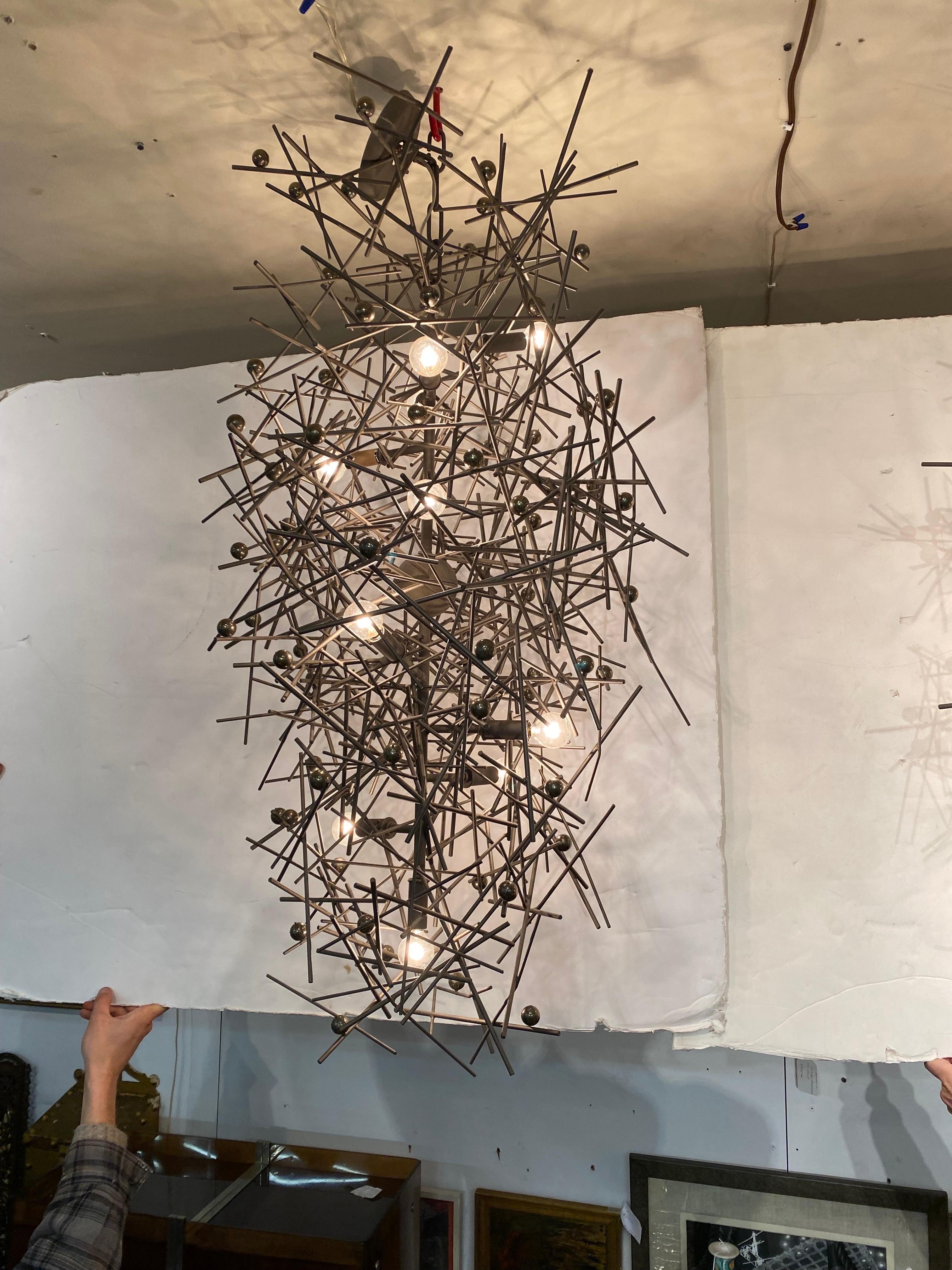A large pair of one of a kind brutalist industrial chandeliers. The welded steel frames with enamel finish decorated with small pyrite spheres, these were custom crafted for a prominent Hamptons estate. 45 inches tall, 19 by 19.