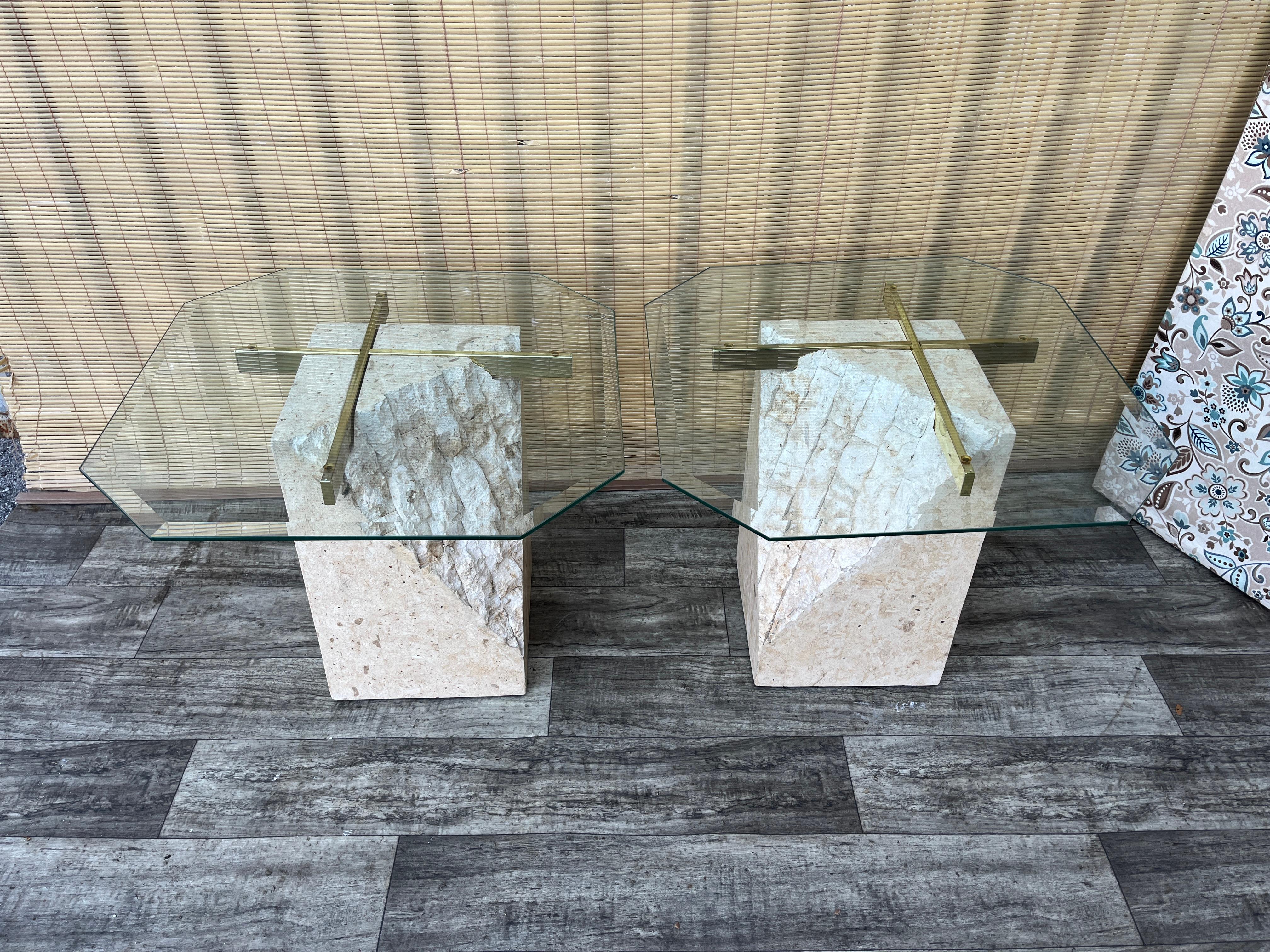 A Pair of Post Modern Tessellated Mactan Stone Side Tables. Circa 1980s
Feature tessellated fossil and rough-cut mactan stone base with intricate shapes, neutral tones, and natural raw stone finish, with brass inlays to support the beveled glass