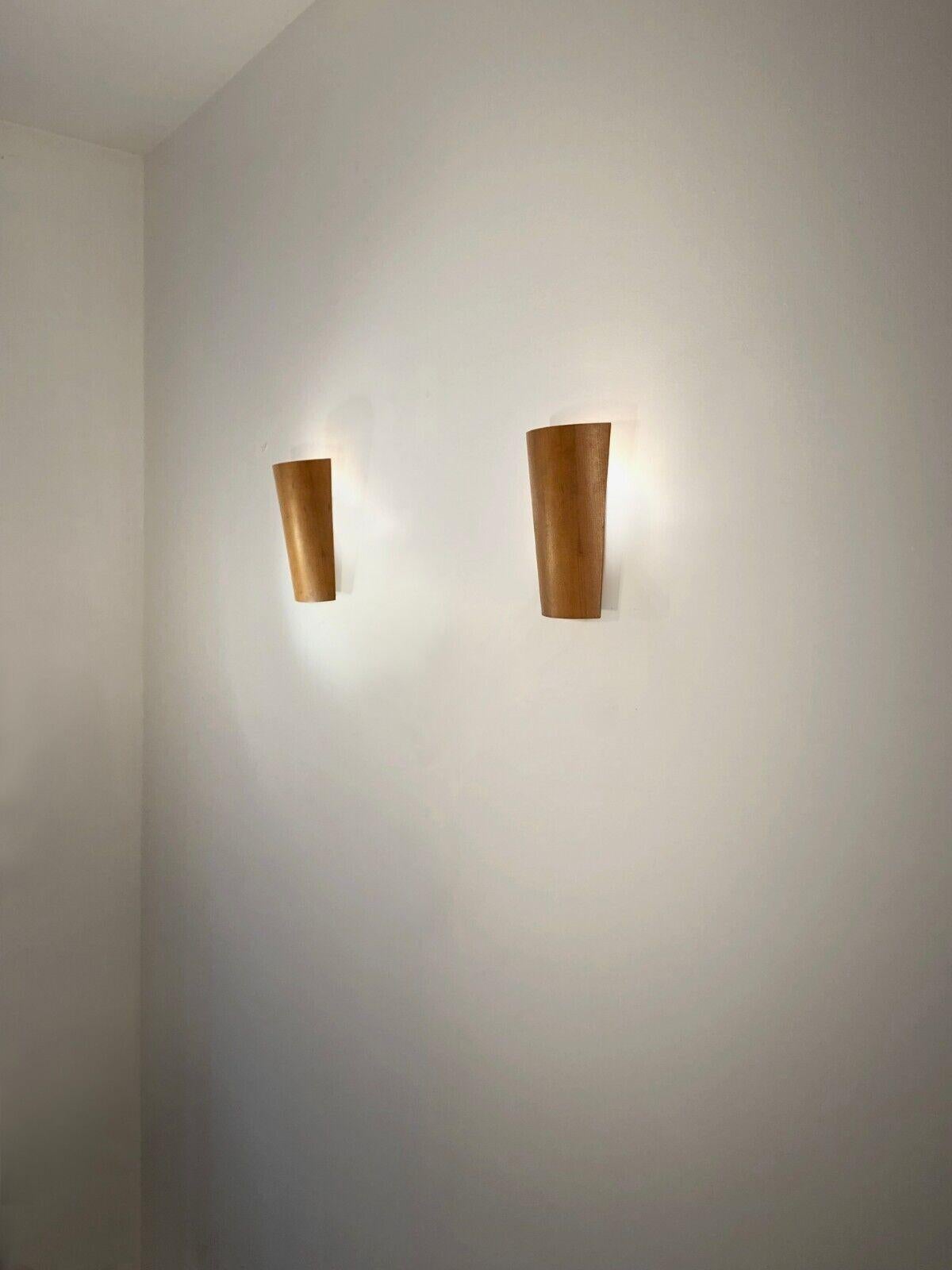 An elegant and simple, post-modern and minimalist pair of warm wall lights, Post-Modernist, Minimalist, Constructivist, Nineties, composed of 2 curved light wood shutters diffusing the light towards the wall, mounted on discreet wall bases in metal,