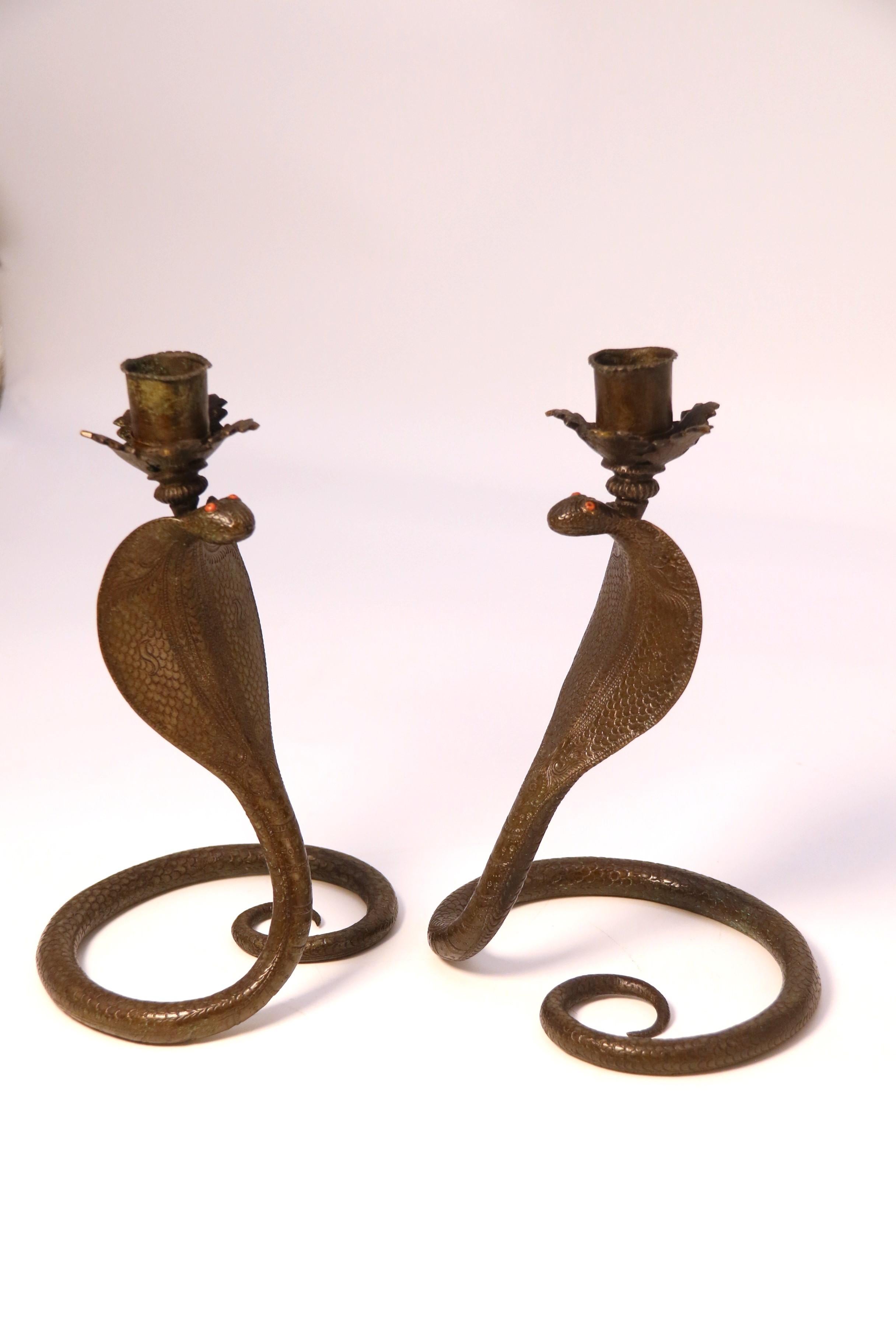 This most decorative pair of Raj period Indian candlesticks has been heavily cast in bronze in the form of a striking cobra snake. Each one is fully hand engraved with stylised scaled markings and patterns. The eyes are inlaid in orange coral and