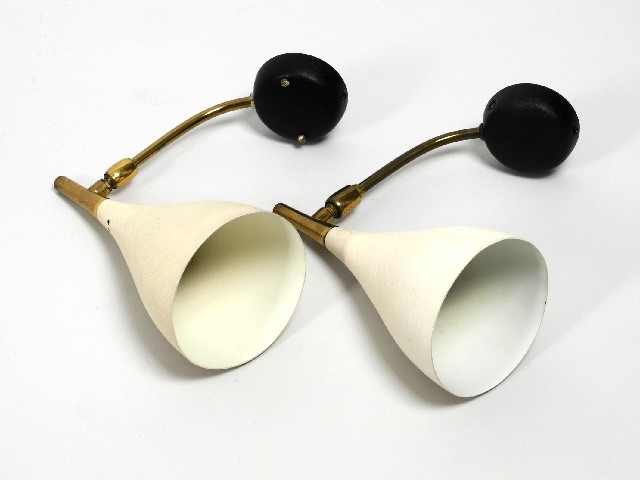 A pair of very rare Mid Century wall lamps by the Dutch designer Louis Kalff. 
Manufacturer Cosack lights. Made in Germany. 
With beige shrink lacquer on the shade and black on the wall mount. 
The shade on the brass neck is steplessly adjustable