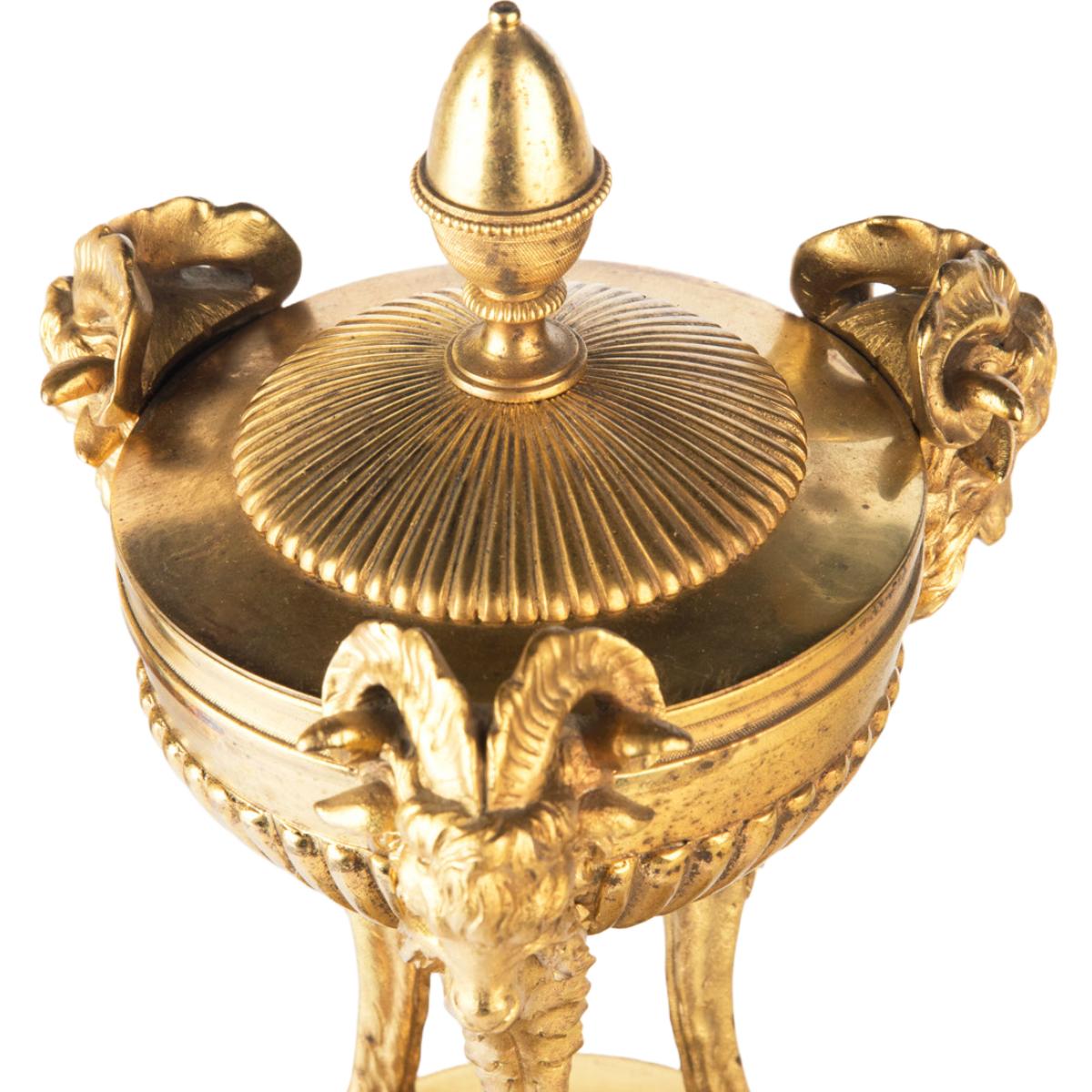 A pair of Regency classical gilt bronze vases, each in the form of a shallow gadrooned bowl with an acorn finial supported by three goat-headed terms with cloven hooves, raised on a short black and white marble column set upon a gilt bronze base. 