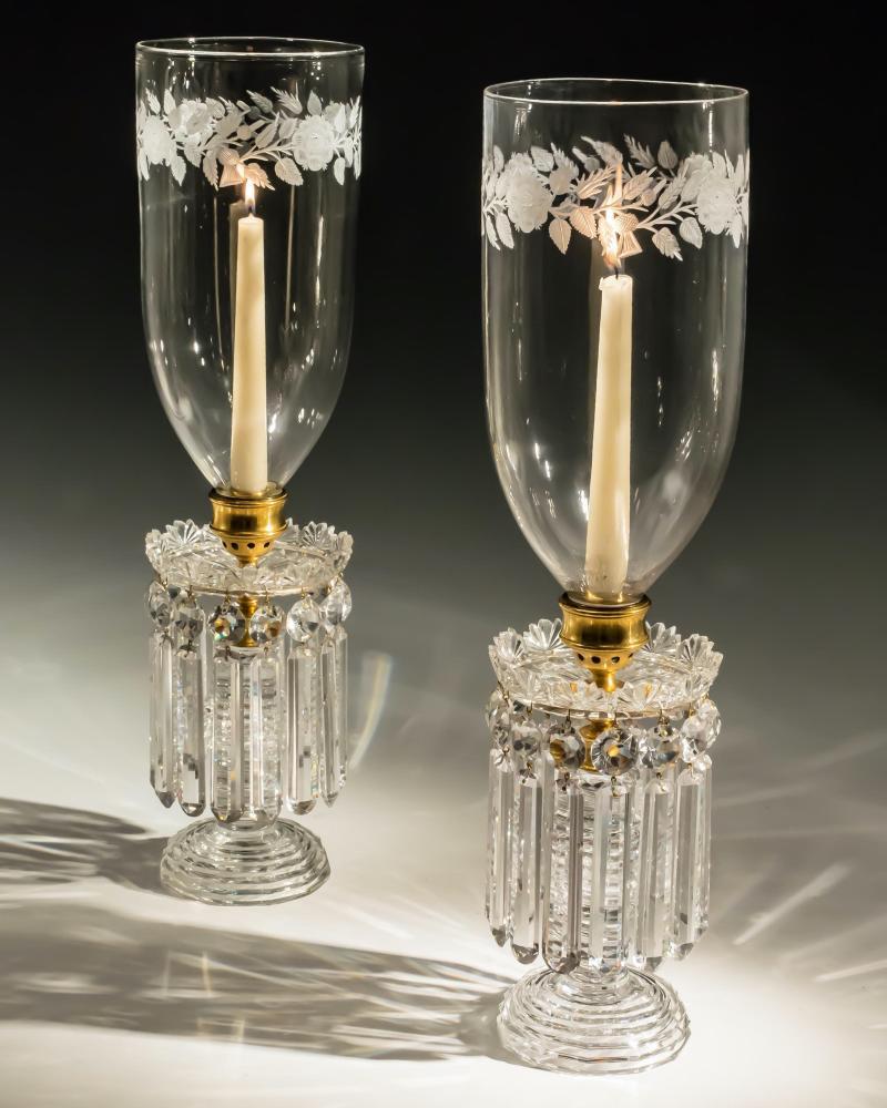 A fine pair of Regency hurricane lights the ormolu-mounted step cut bases supporting radial cut drip pans with fan edge hung with round end rule drops and flat back spangles, the shades of bullet form having finely engraved rose and thistle bands.
