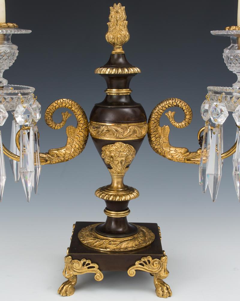 A fine pair of Ormolu and bronze bases issuing serpentine scroll arms supporting diamond cut drips and candle nozzles hung with star buttons and triangular icicles.