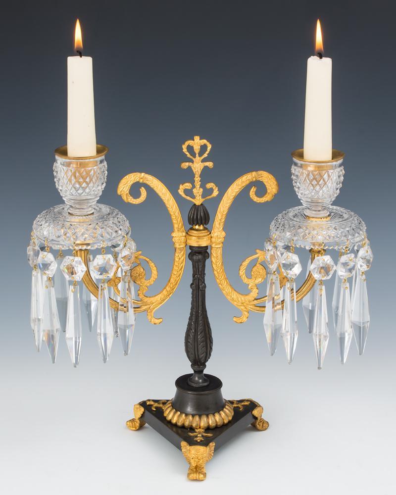 A pair of ormolu and bronze Regency candelabra on tripod base issuing two J arms of serpentine form supporting diamond cut drip pans and candle nozzles hung with triangular icicles and star spangles.
Height 26.5 cm (10 1/2