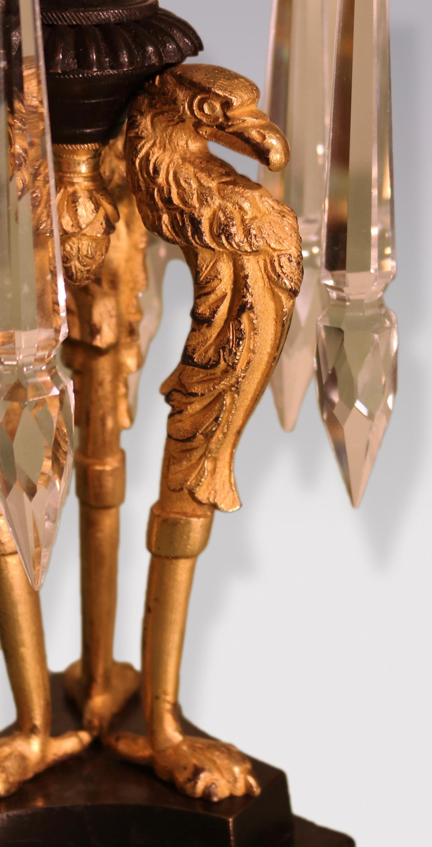 Ein Paar Bronze- und Ormolu-Lüsterleuchter aus der Regency-Periode des frühen 19. Jahrhunderts mit floralen Leuchtspitzen über Blätterdächern, die auf dreifachen Greifenstützen stehen, die auf abgestuften konkaven Sockeln enden.