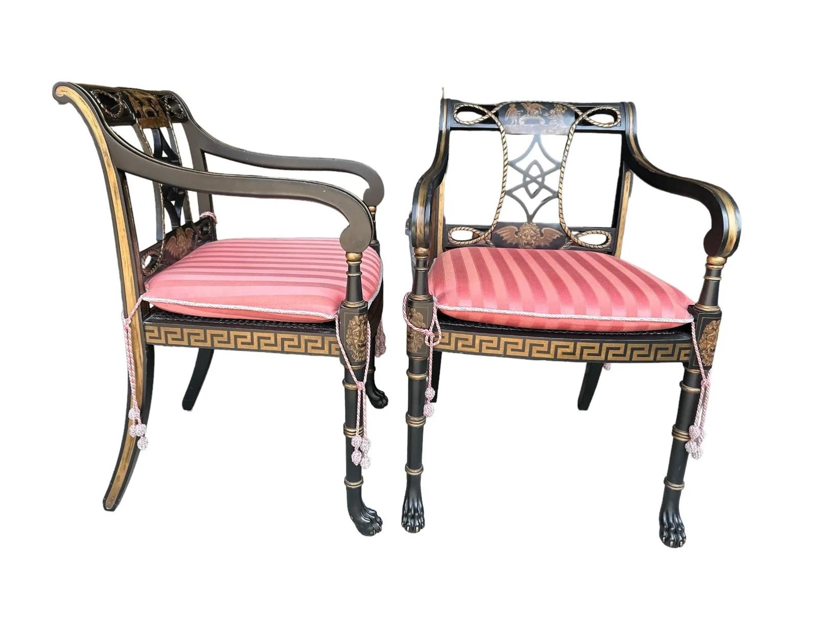 Pair of regency style painted and gold leafed arm chairs. Black painted chairs feature gold colored Lion's heads on inside chair back and legs, with gold Greek key design along bottom apron. Hairy paw feet front feet complete the uniqueness of these