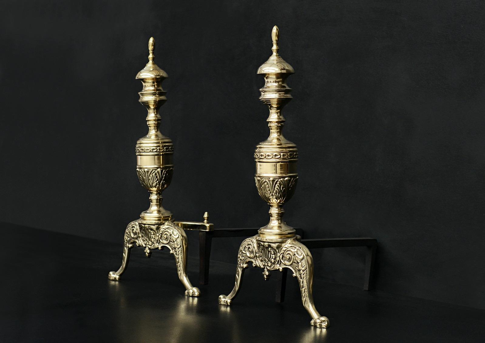 A pair of Regency style English brass firedogs, the claw shaped feet and cast filigree work surmounted by stiff acanthus leaf stem and leaf urn finials. English, circa 1900.

Measures: Height: 552 mm 21 ¾