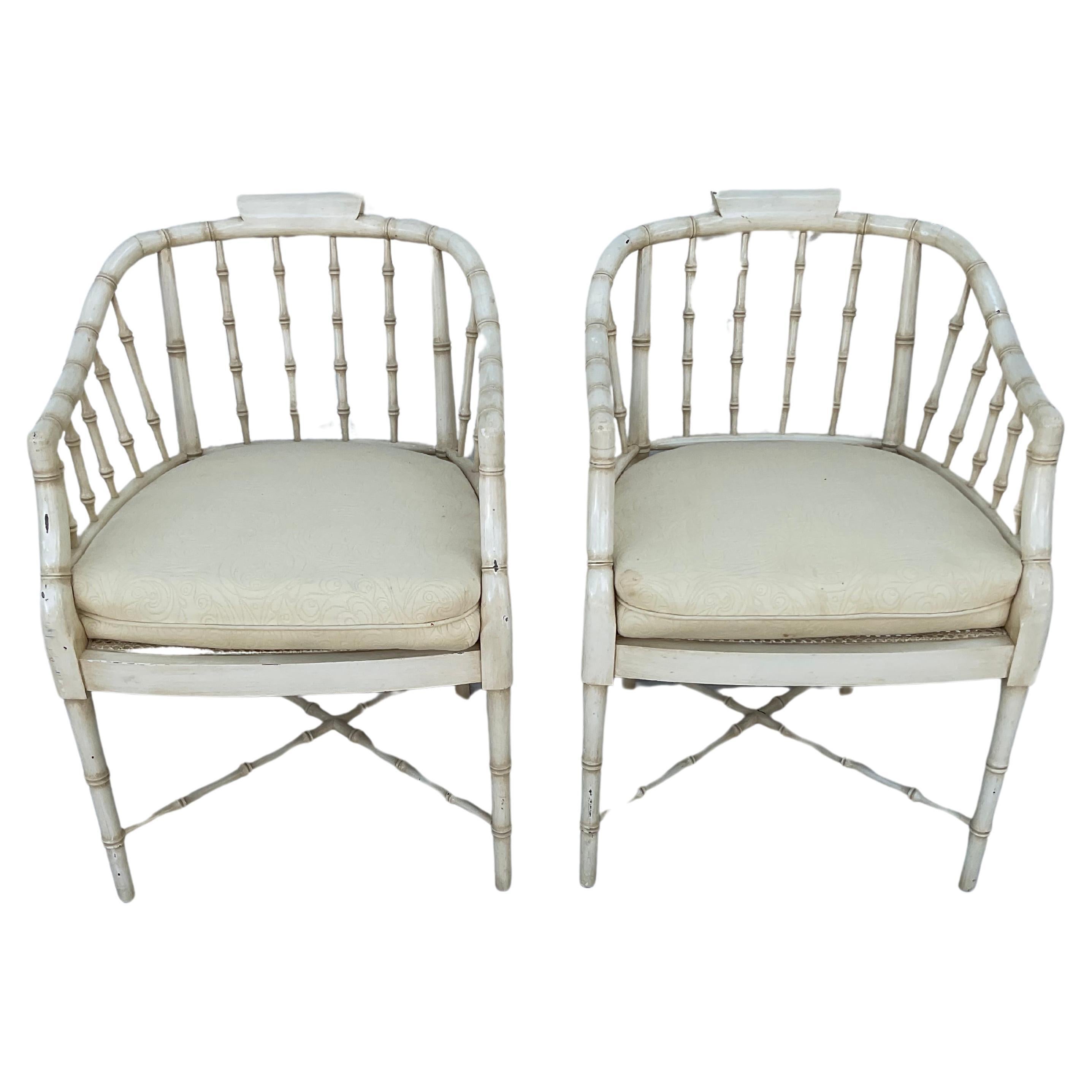 Fine pair of Regency style faux bamboo armchairs, painted a cream color. Features tub-shaped backs and cane seats.  Chairs are raised on four slender legs connected by an X-shaped stretcher. They come with removable cream cushions.