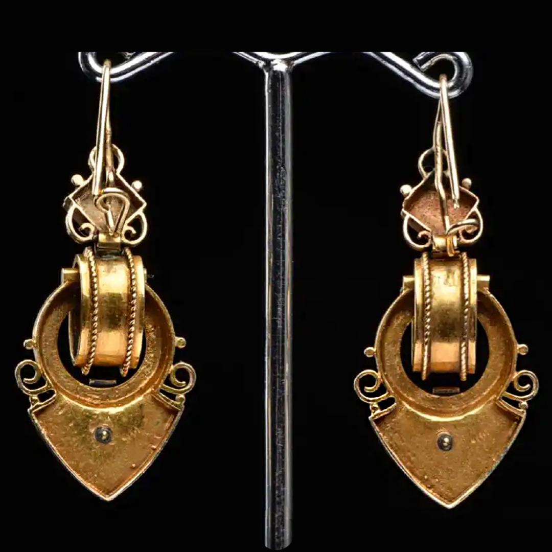 A pair of Renaissance Revival style drop earrings set in 14 Karat yellow gold. Circa 1860-1880. Each earring featuring a diamond shaped top embellished with a bezel set round mixed cut blue saphire. Surmounting an articulated drop featuring a beaded