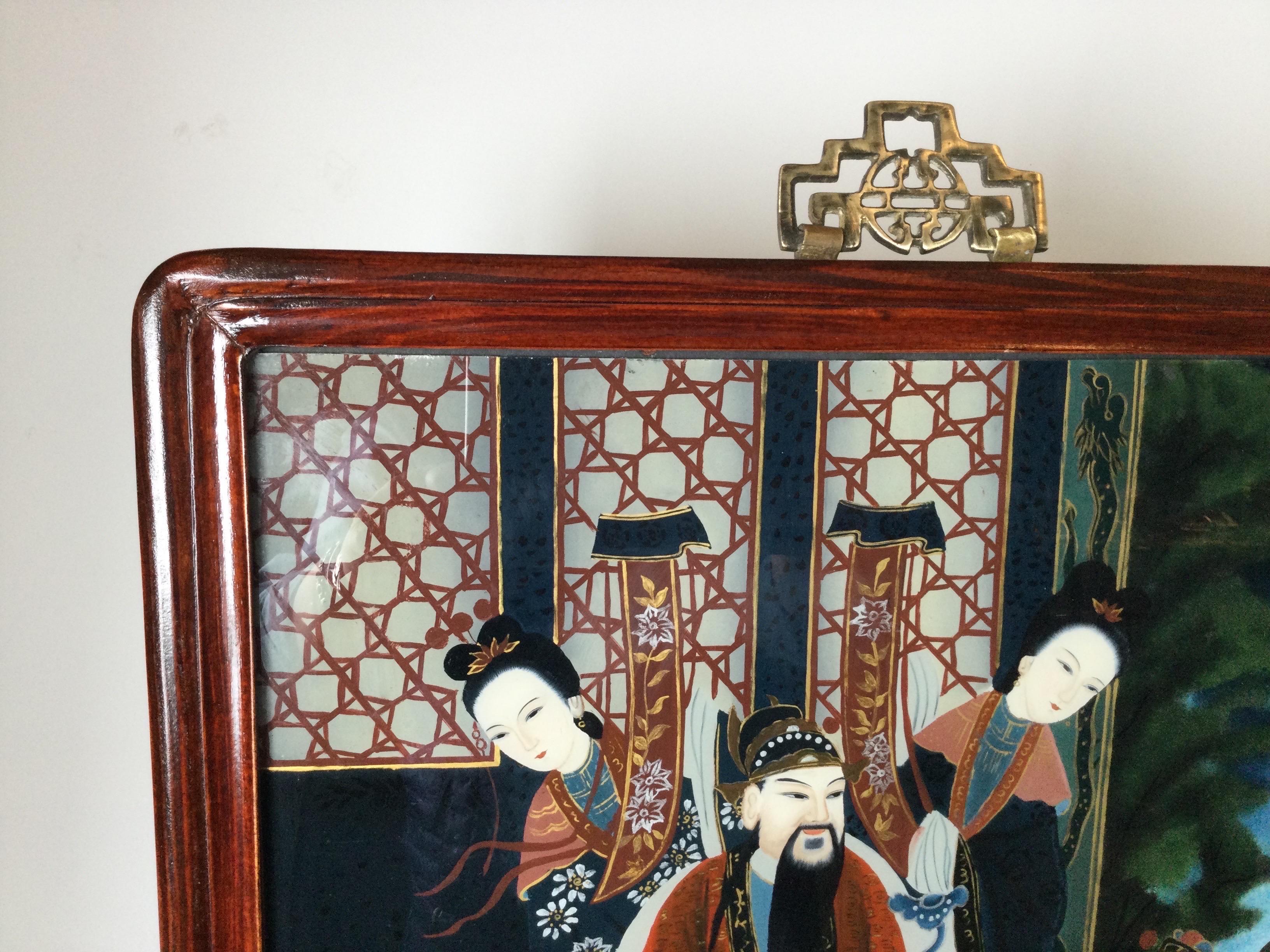 A pair of beautifully painted Japanese noble men and women groupings. The paintings are reverse painted on glass and framed in Asian style Hung-mu wood frames with cast brass hangers at the tops.