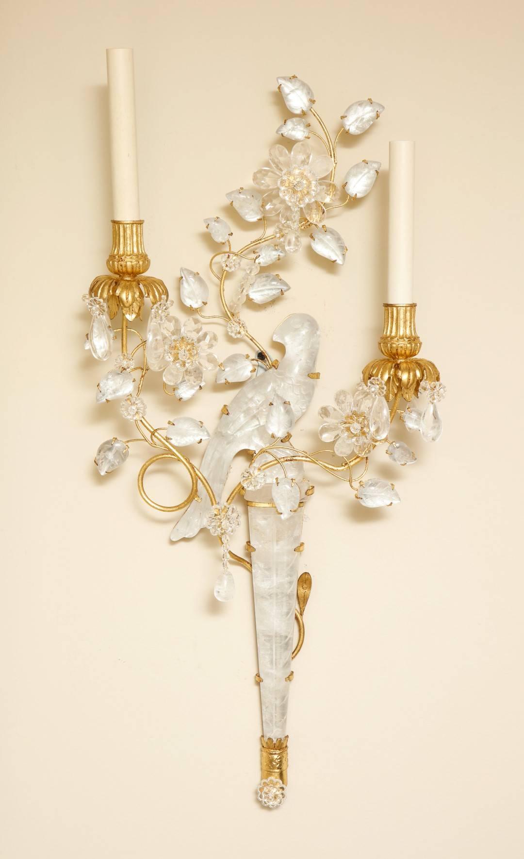 A pair of new right and left facing two-light gilt-metal and rock crystal sconces, depicting perched birds carved in rock crystal and surrounded by sprays of branches and leaves, with gilt lotus-capped bobeches.
 