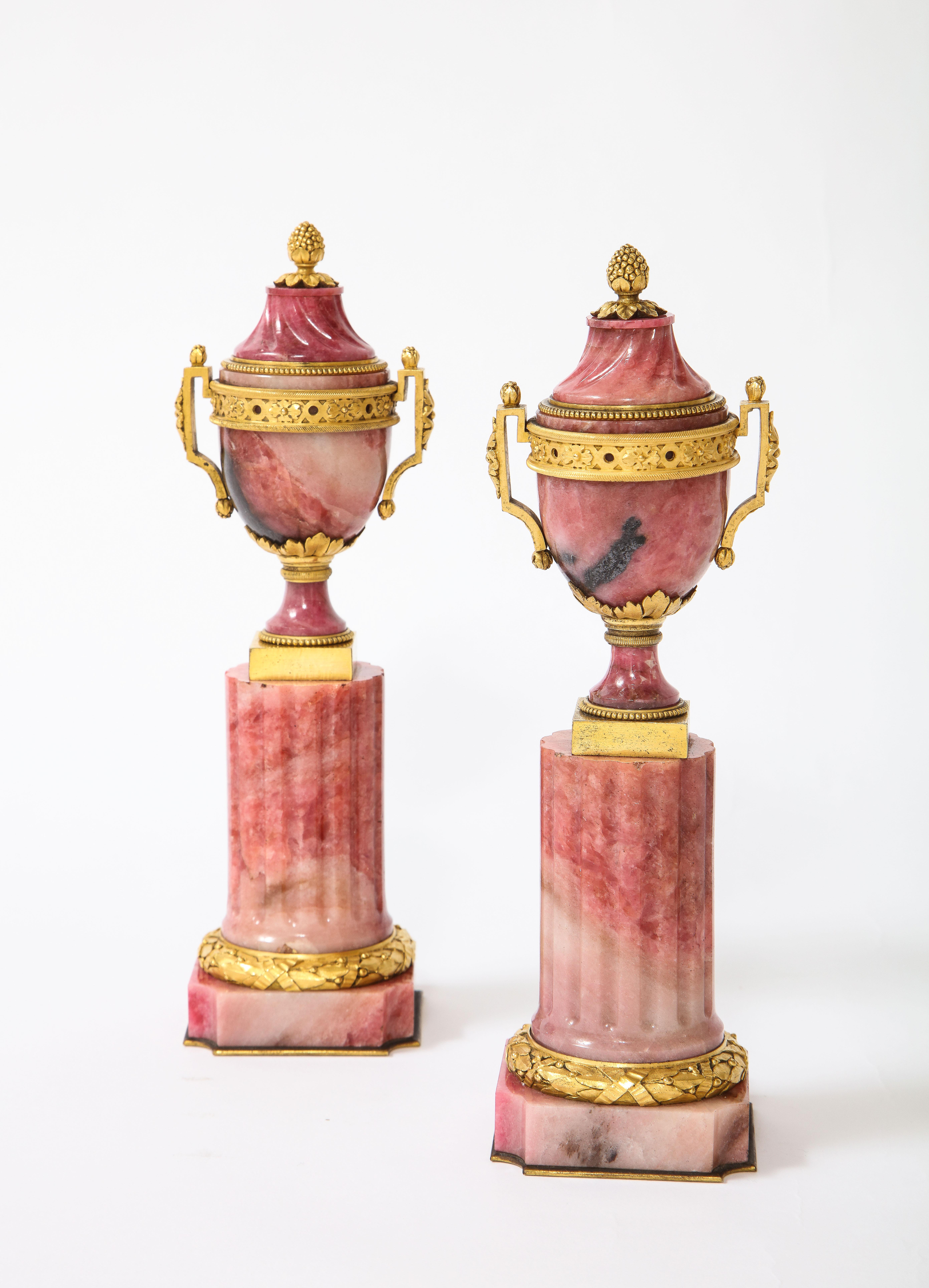 A Marvelous and Gorgeous pair of Russian Louis XVI style dore bronze mounted hand-carved Rhodonite Cassolettes. Each section, from the urn to the plinth, is exceptionally hand-carved and hand-polished to create a vibrant sheen and shine. The plinth