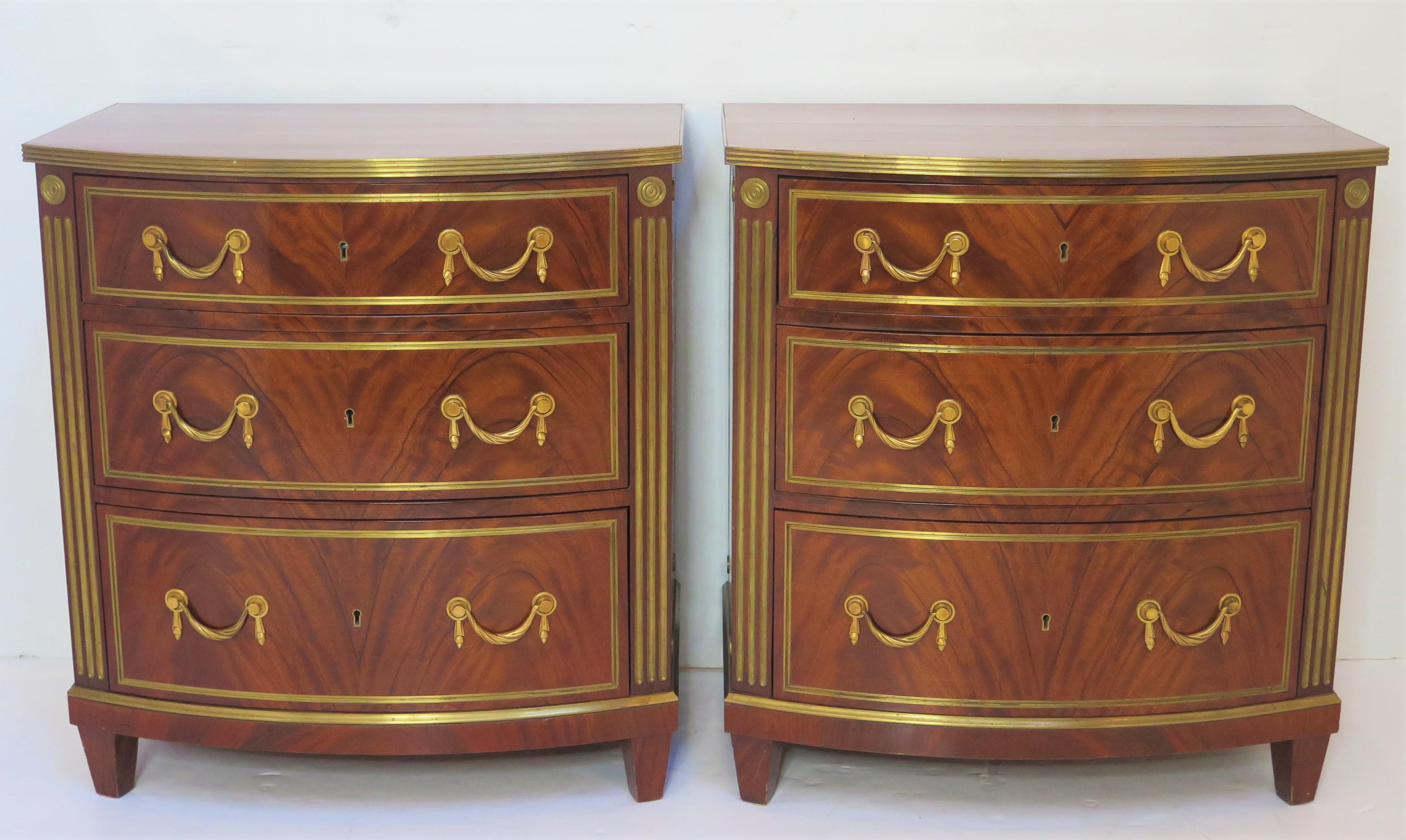 A pair of Russian Neoclassical gilt-brass mounted mahogany D-shaped / bow front chests of drawers, banded gilt brass inlaid frieze above three drawers with gilt brass swag bail pulls, note the beautiful book-matched crotch mahogany drawer fronts,