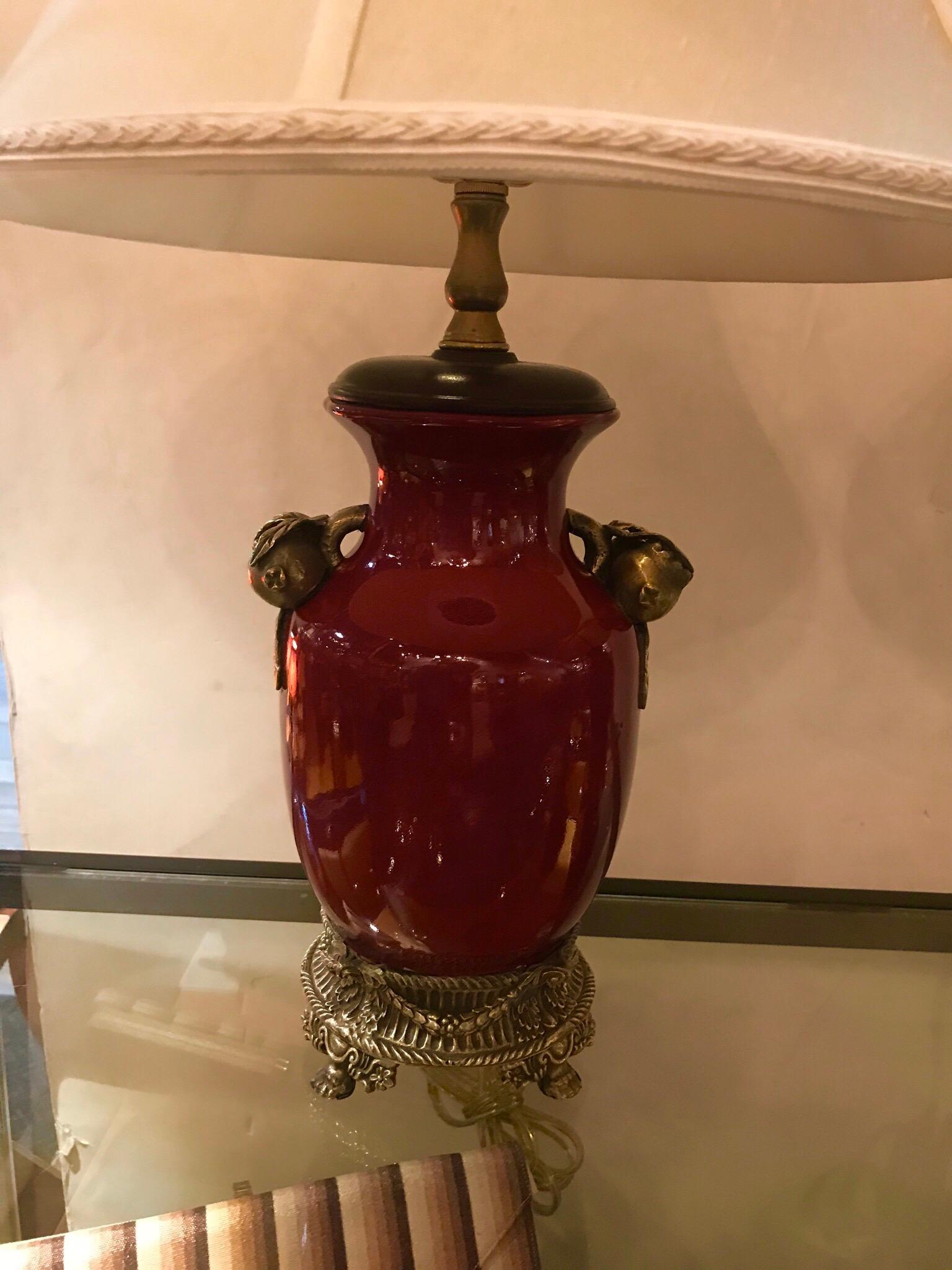 A stunning pair of Sang De Boeuf porcelain lamps with cast brass mounts. The oxblood colored glazed porcelain bodies with cast sold brass handles in the form of pomegranates. The bases with nicely cast rope and draped decoration all around. New