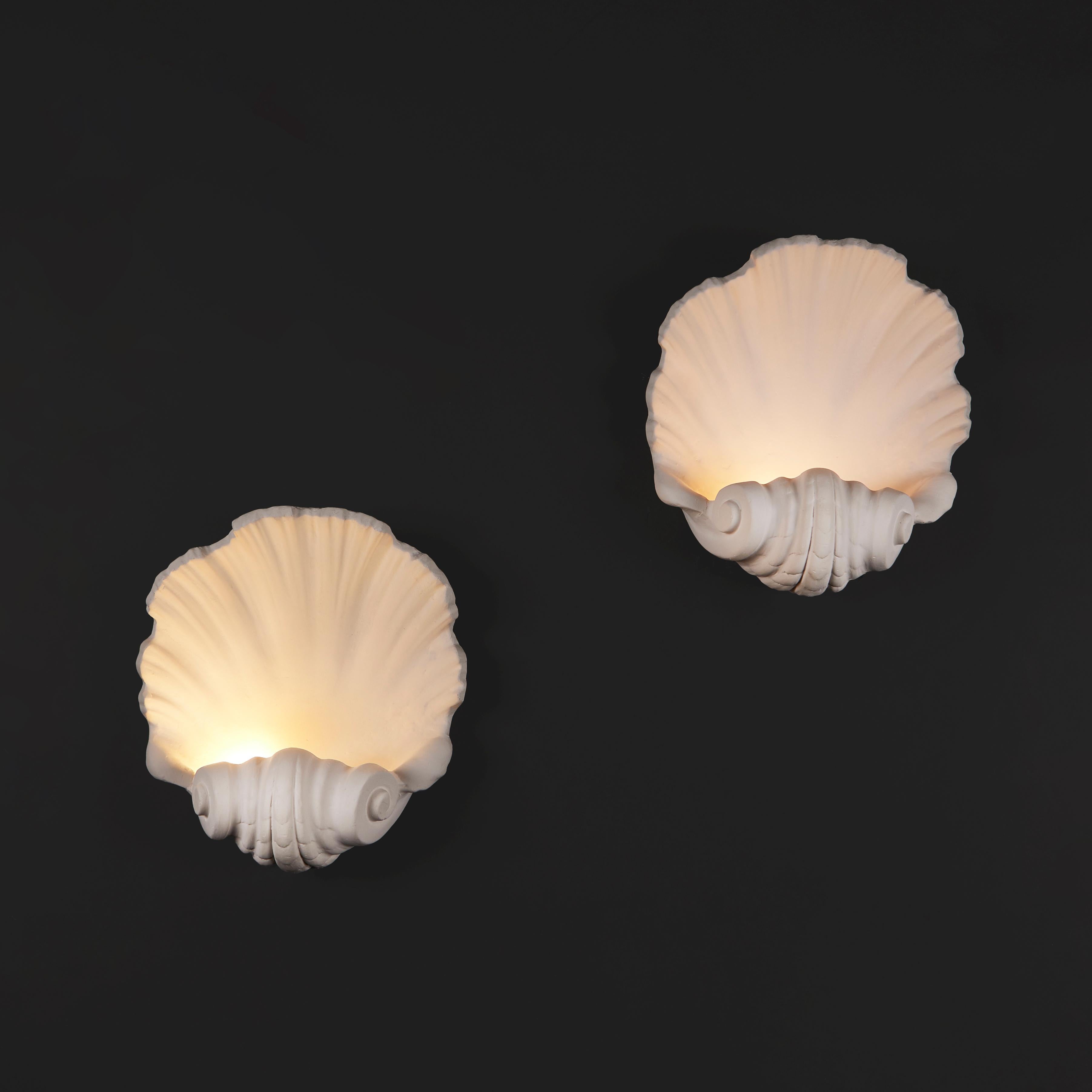 England, made to order.

A pair of plaster wall lights in the form of a large scallop shell, with scrolling base, the light hidden within the scroll. 

Height    35.00cm
Width      31.00cm
Depth      15.00cm

Please note:
Currently wired for the UK