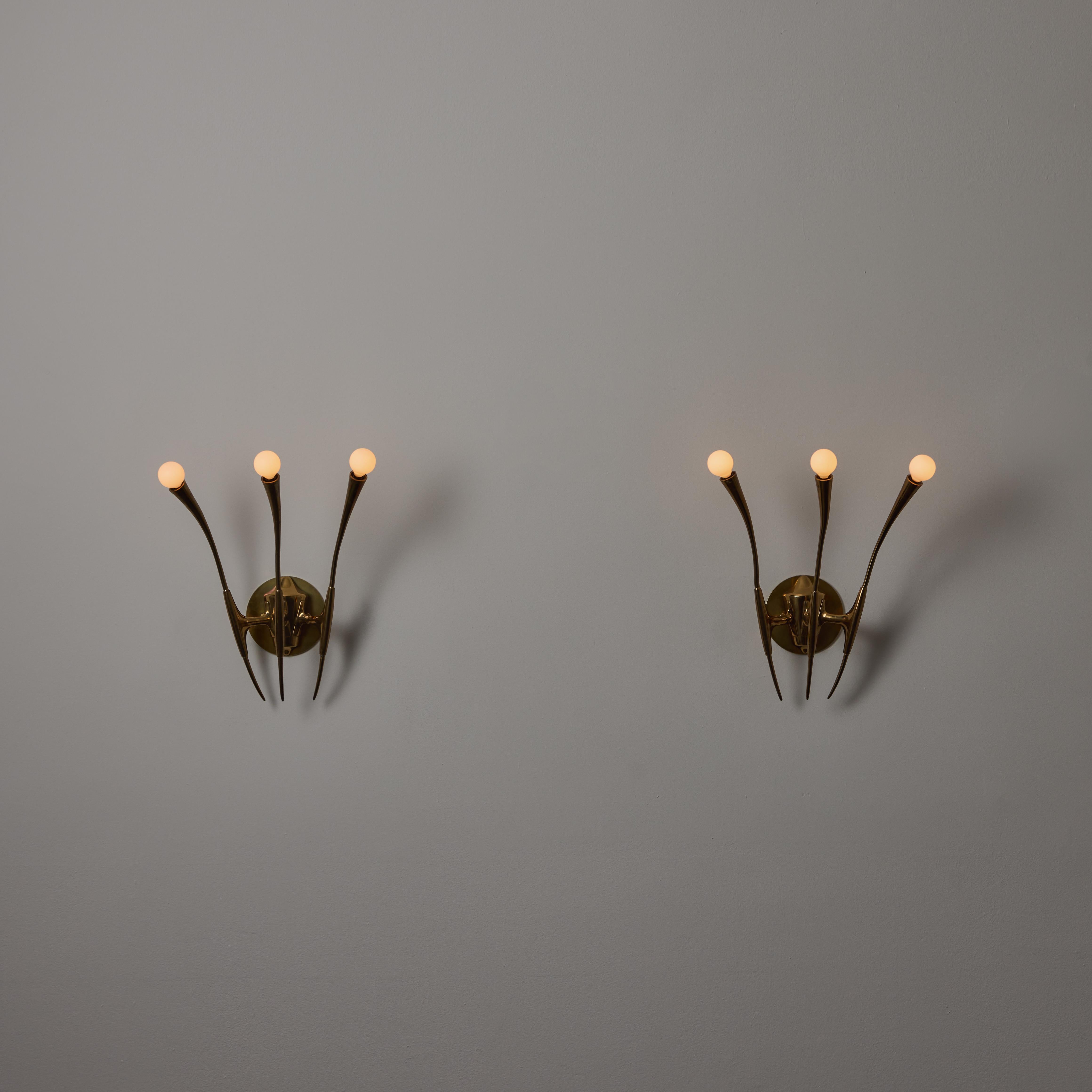 A Pair of Sconces by Oscar Torlasco. Designed and manufactured in Italy Circa the 1950s. All brass Gothic sconces comprising of trident socket housing spraying outwards from a central mount. Heavy and beautiful brass aging. Each sconce is an e14