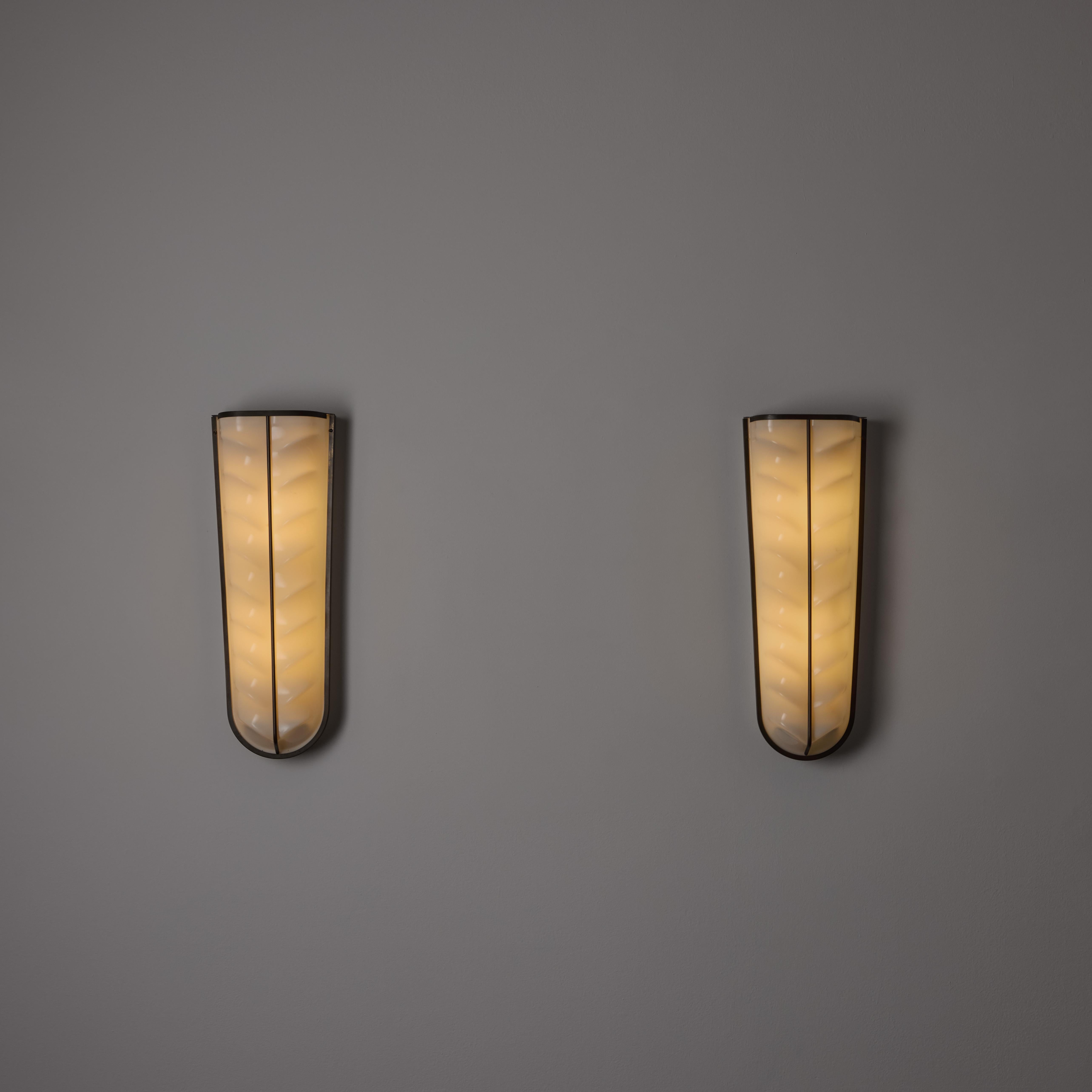 A Pair of Sconces by Stilux. Designed and manufactured in Italy, circa the 1960s. Striking anatomically molded acrylic diffusers with patinated brass accents. These sconces are lightweight due to the material choices. Each sconce holds a quadruple