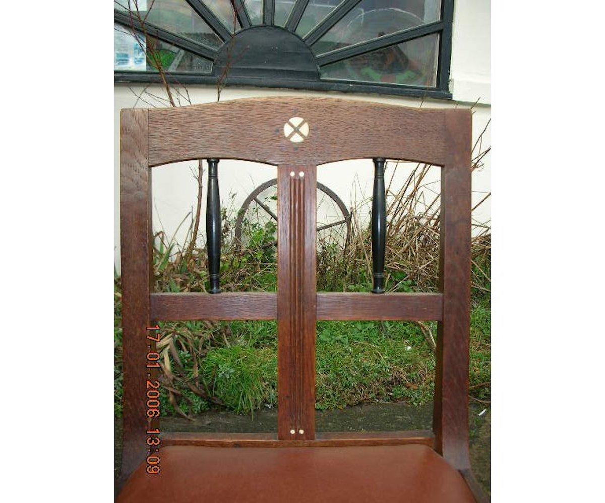 A pair of Secessionist style oak side chairs with curvaceous backs, stylized inlays and ebonized spindles. 
Professionally upholstered in quality leather.