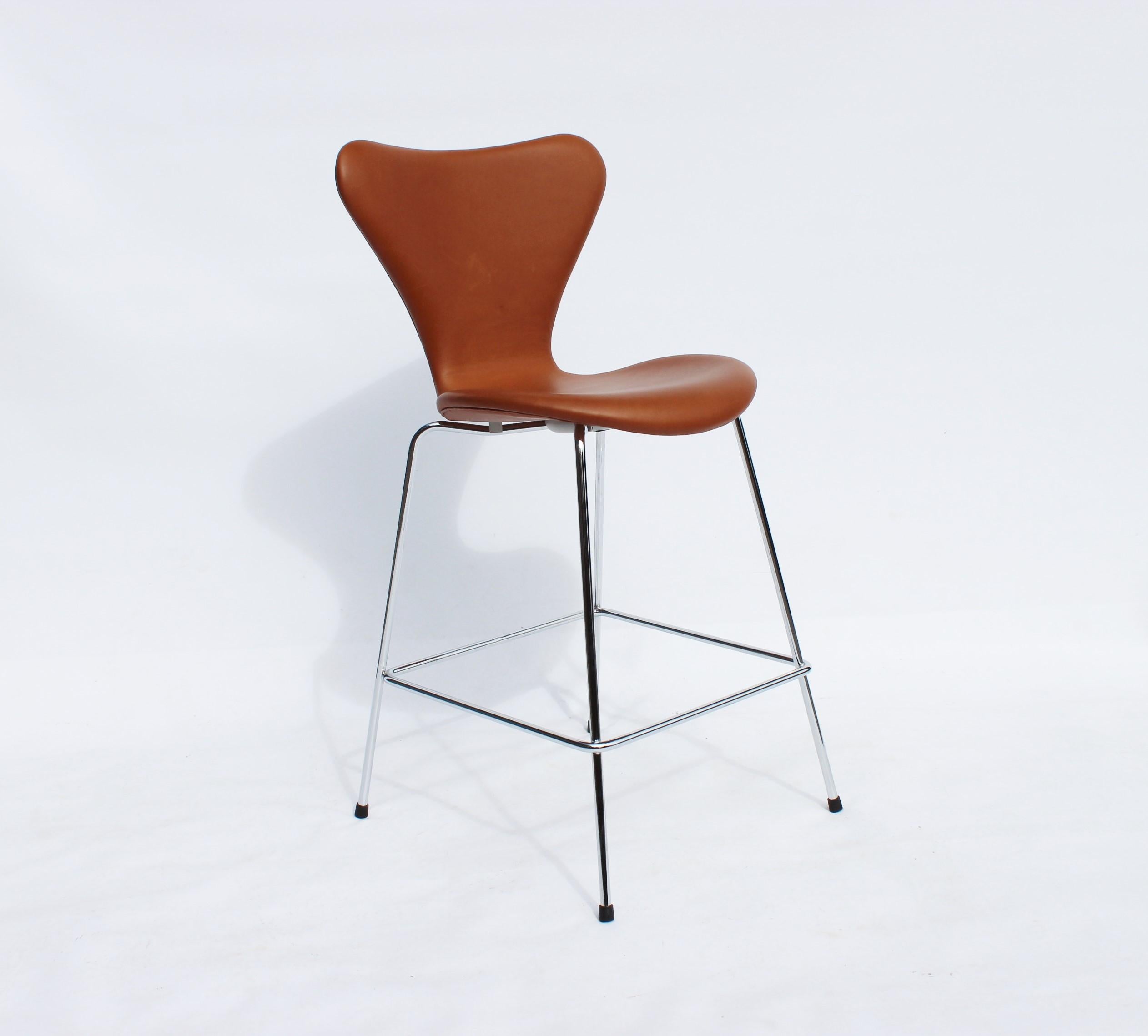 A pair of seven bar stools, model 3187, with cognac leather designed by Arne Jacobsen and manufactured by Fritz Hansen in 2019. The chairs are in excellent condition.