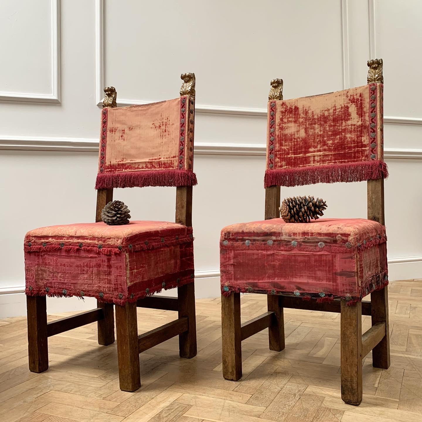 A sumptuous pair of seventeenth century Italian walnut chairs, the backs surmounted by carved and gilt finials with red velvet seats and backs, with red tassel fringing - Ex Ullstein Family Collection

Italian, 17th century.