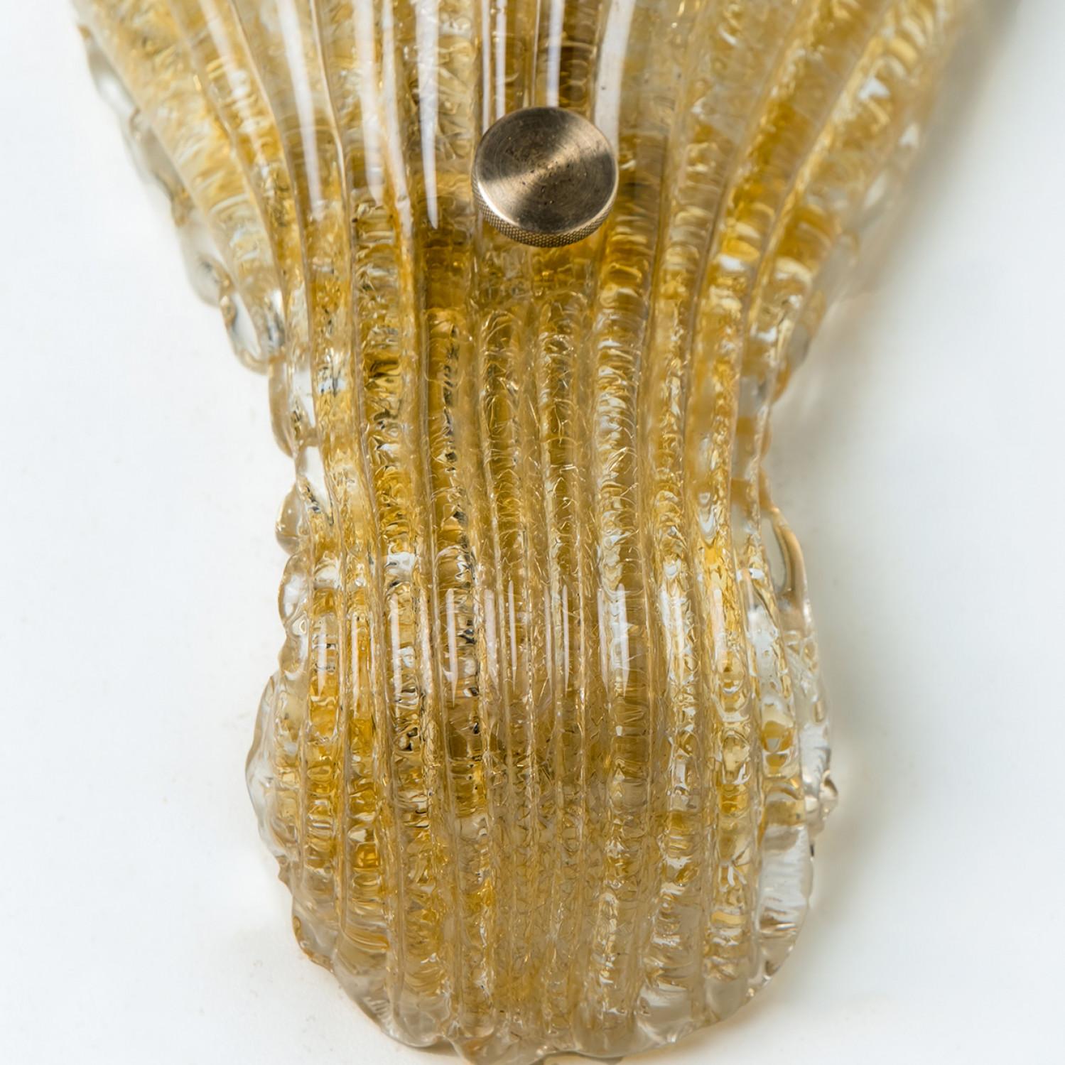 A pair of elegant hand-blown Murano glass wall light of Barovier & Toso, Italy. Manufactured late 1960s, early 1970s.
The light fixture consists of a blown Murano glass shell, a wide cover, mounted on a brass frame. The glass is gold-flaked, which