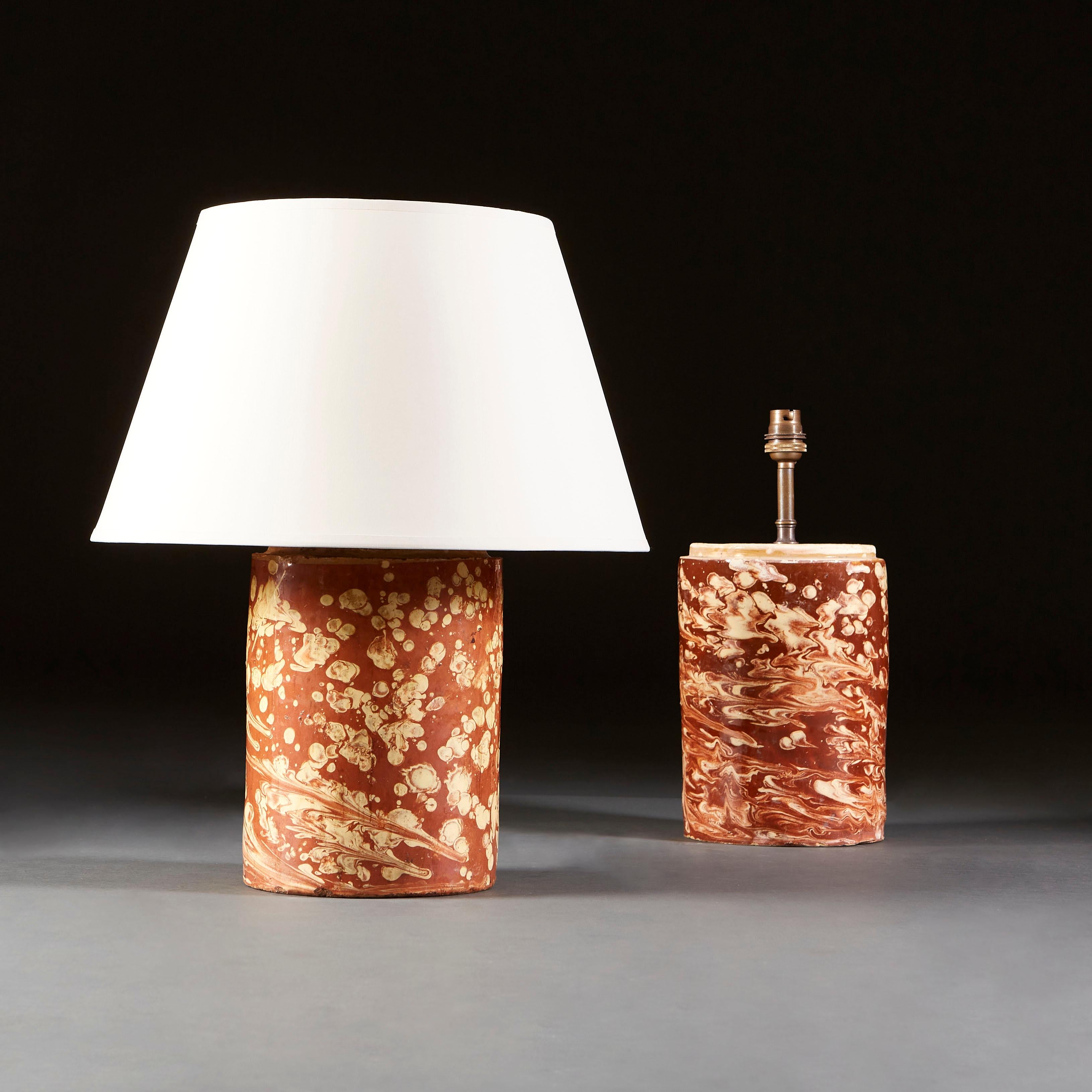 A pair of early nineteenth century Italian pharmacy jars of cylindrical form with a sienna and cream marbleised glaze across the surface of the vases, now as lamps.

Currently wired for the UK.

Please note: lampshades not included.