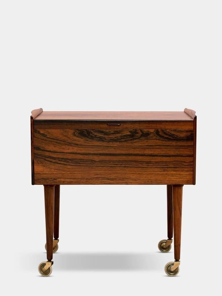 A. Andersen & Bohm

A pair of beautiful side tables in Mid-Century Modern Danish design of rosewood, inside with solid rosewood trays, legs with polished brass and wheels.
Designed and manufactured in the 1960s. An original vintage piece
