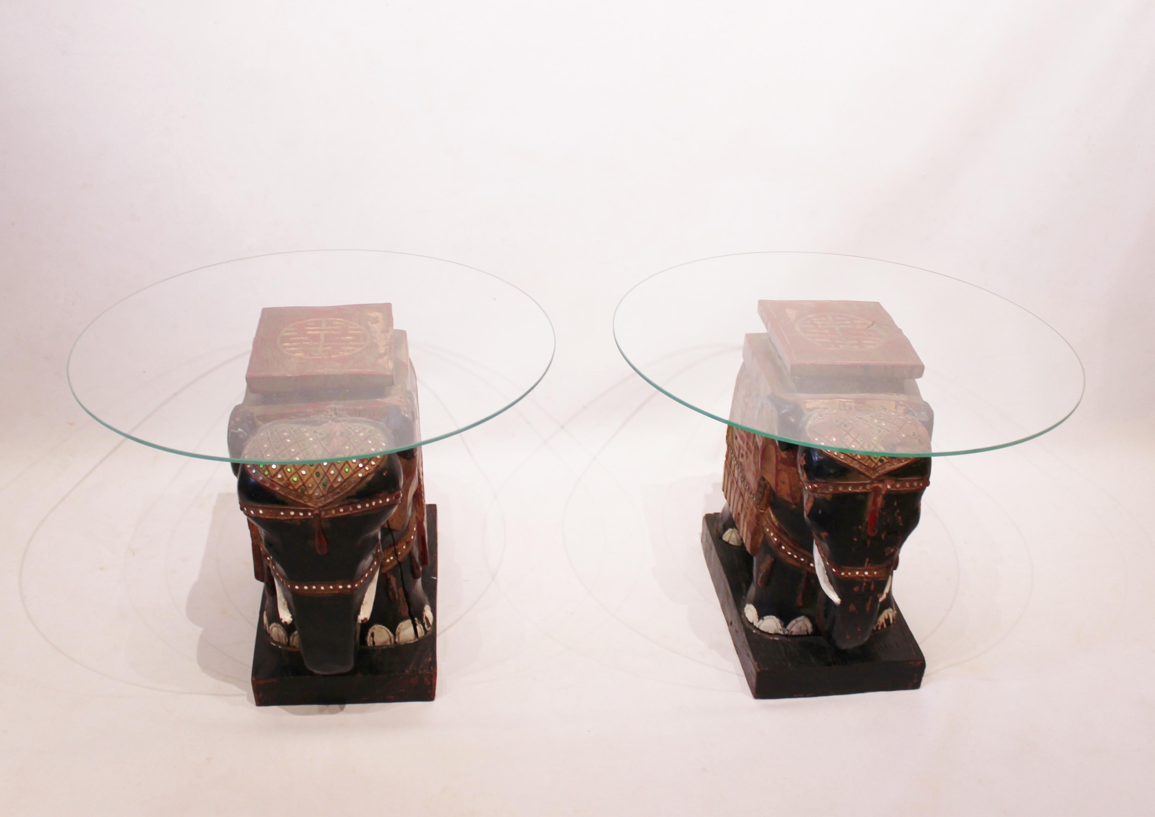 A pair of side tables with glass plates and Chinese elephant bases made of original painted wood and patina from the circa 1880s is a truly unique and captivating find.

The combination of the glass plates and the Chinese elephant bases creates an