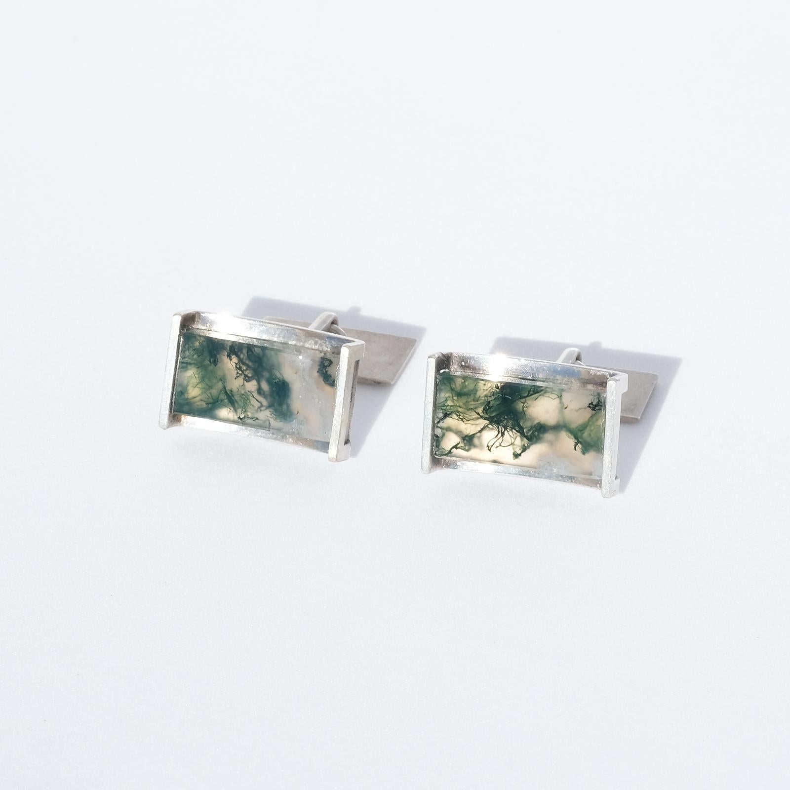 These silver cufflinks have a rectangular shape and they are decorated with large moss agates.

The moss agate stone is, as well as the simple and austere shape, a typical Elis Kauppi characteristic.   

The cufflinks' appearance is very chic and