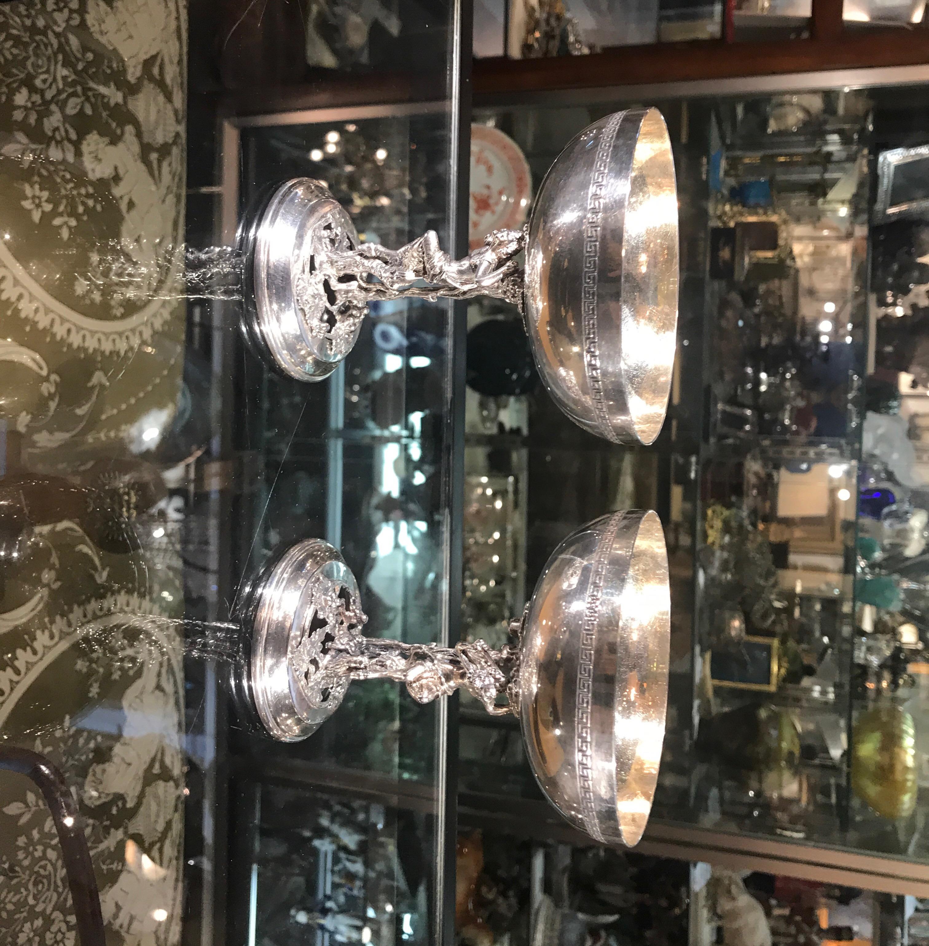 A pair of Bacchanalian motif champagne coups made in Spain. The bowl tops with Greek key pattern on the outside with a cast figure of Bacchus at the stem.