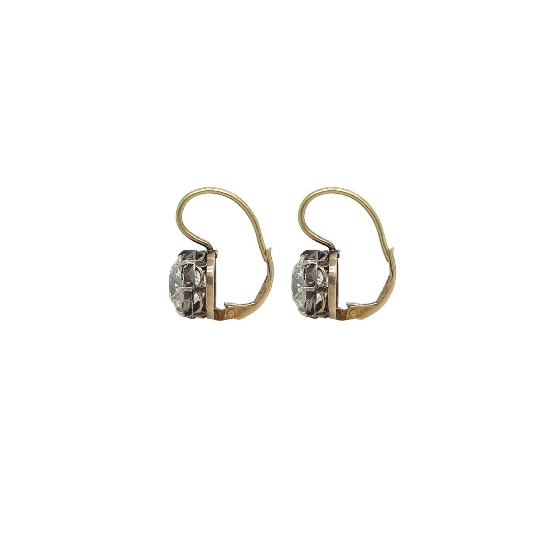 A pair of silver topped gold and diamond earrings.  One is set with an old mine cut diamond weighing 3.26 carats and the other is set with an old mind cut diamond weighing 3.53 carats.