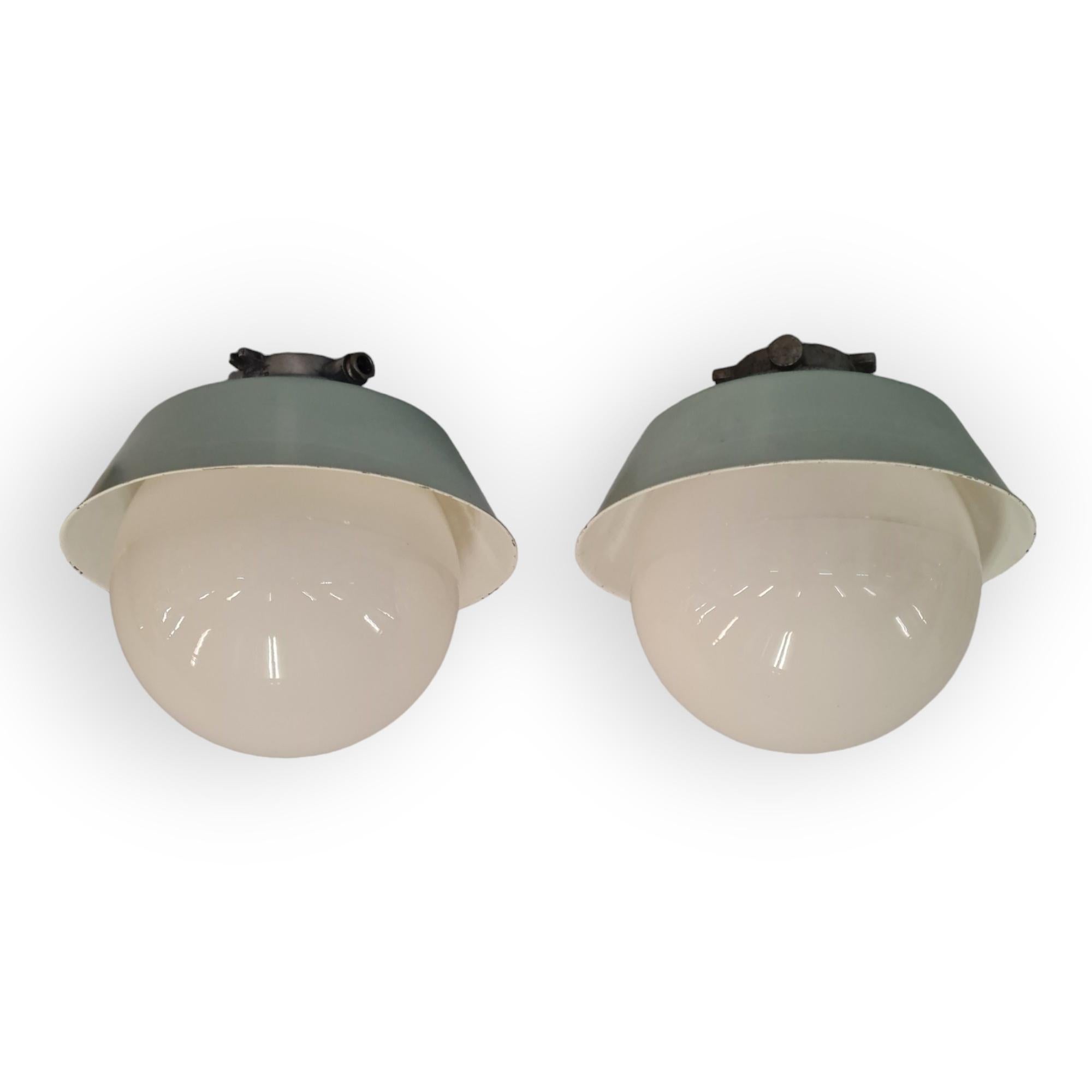 A pair of sizable industrial style Paavo Tynell outdoor / indoor lamps. These lamps model 2421-2453 are quite large with a big opaline glass ball shade that is easily screwed in and out of place to change the light bulb. The lamps have a beautiful