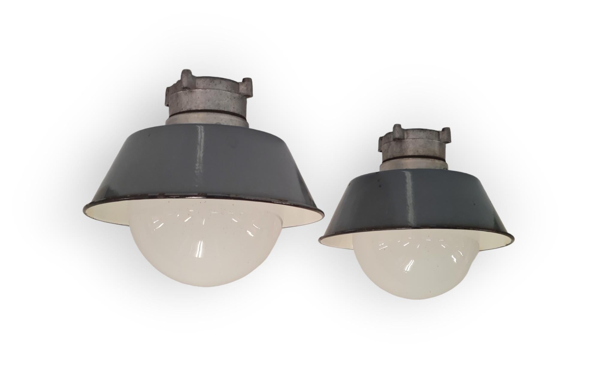A pair of industrial style Paavo Tynell outdoor / indoor lamps. These lamps model H9-100 are a quite smaller than the other industrial pair we have listed on 1stdibs. Otherwise, they are similar in having an opaline glass ball shade that is easily