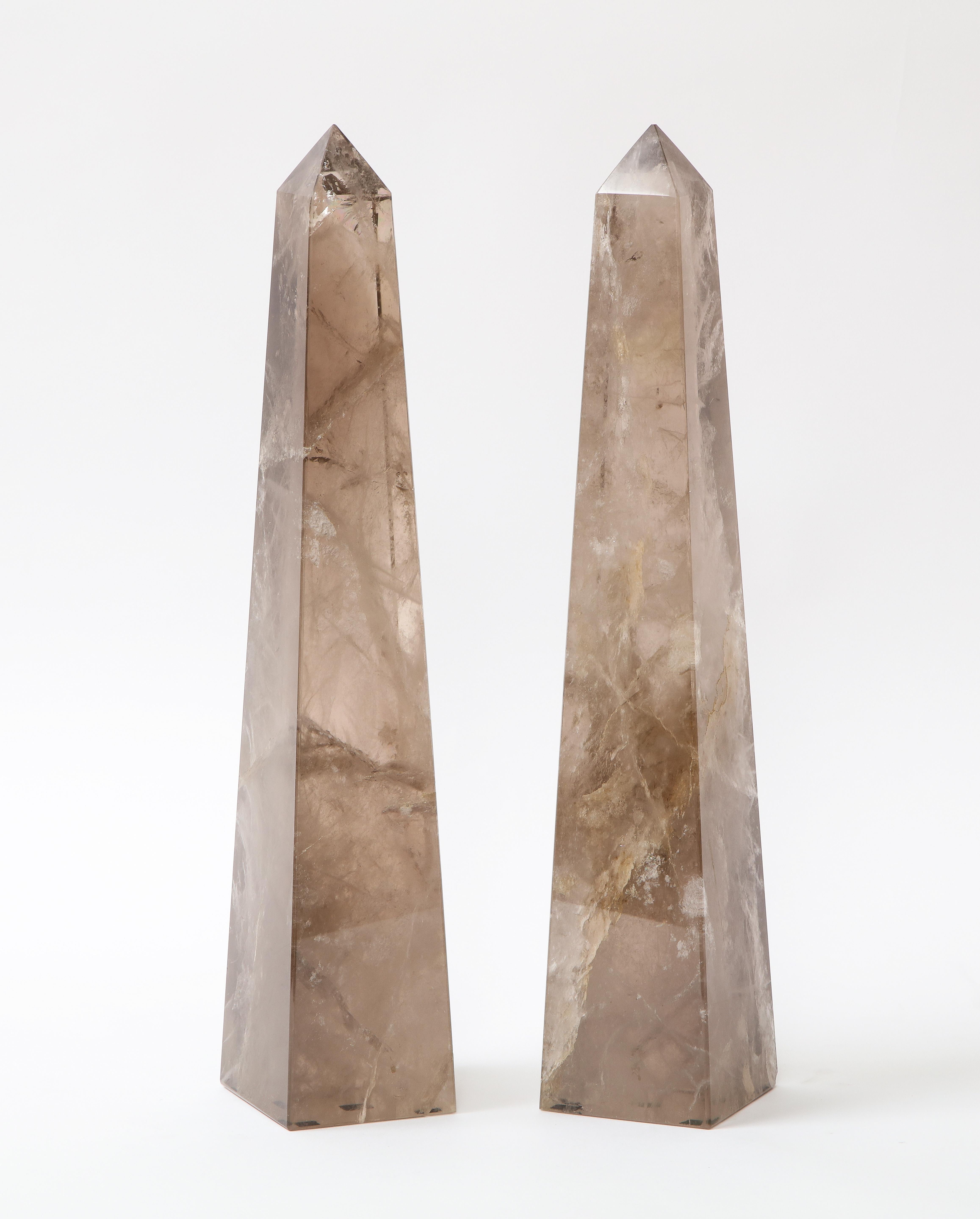 A gorgeous and quite decorative pair of Mid-Century Modern French Smokey rock crystal quartz hand carved and hand-polished obelisks. Each obelisk is made of a natural Smokey rock crystal quartz which has been hand-diamond cut and hand-polished with