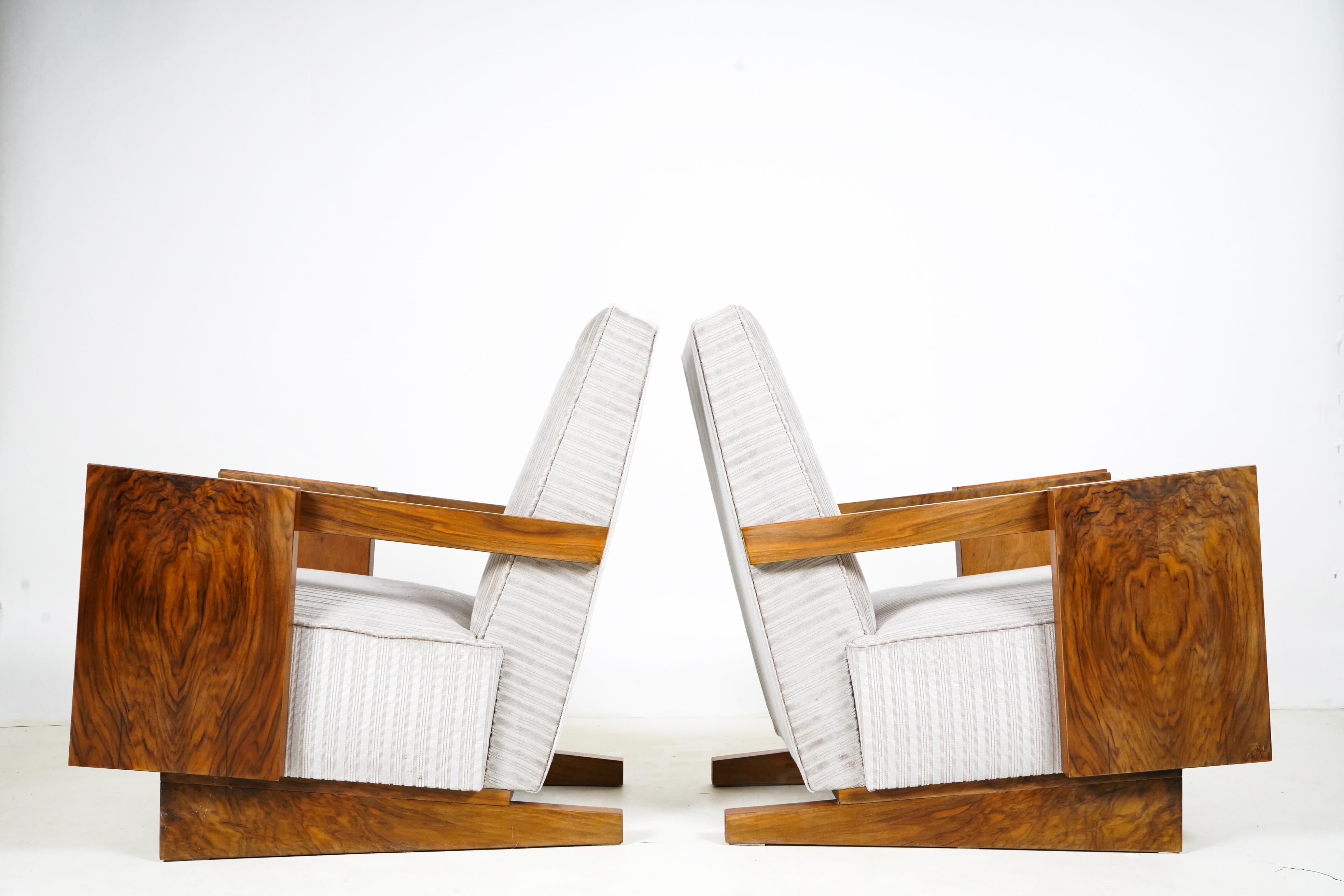 This pair of boldly angular armchairs date to the Socialist Period in Hungary, around 1970. Hungarian furniture makers mastered the art of making veneered furniture as early as the Biedermeier Period (early 1800s). They thrived through the interwar
