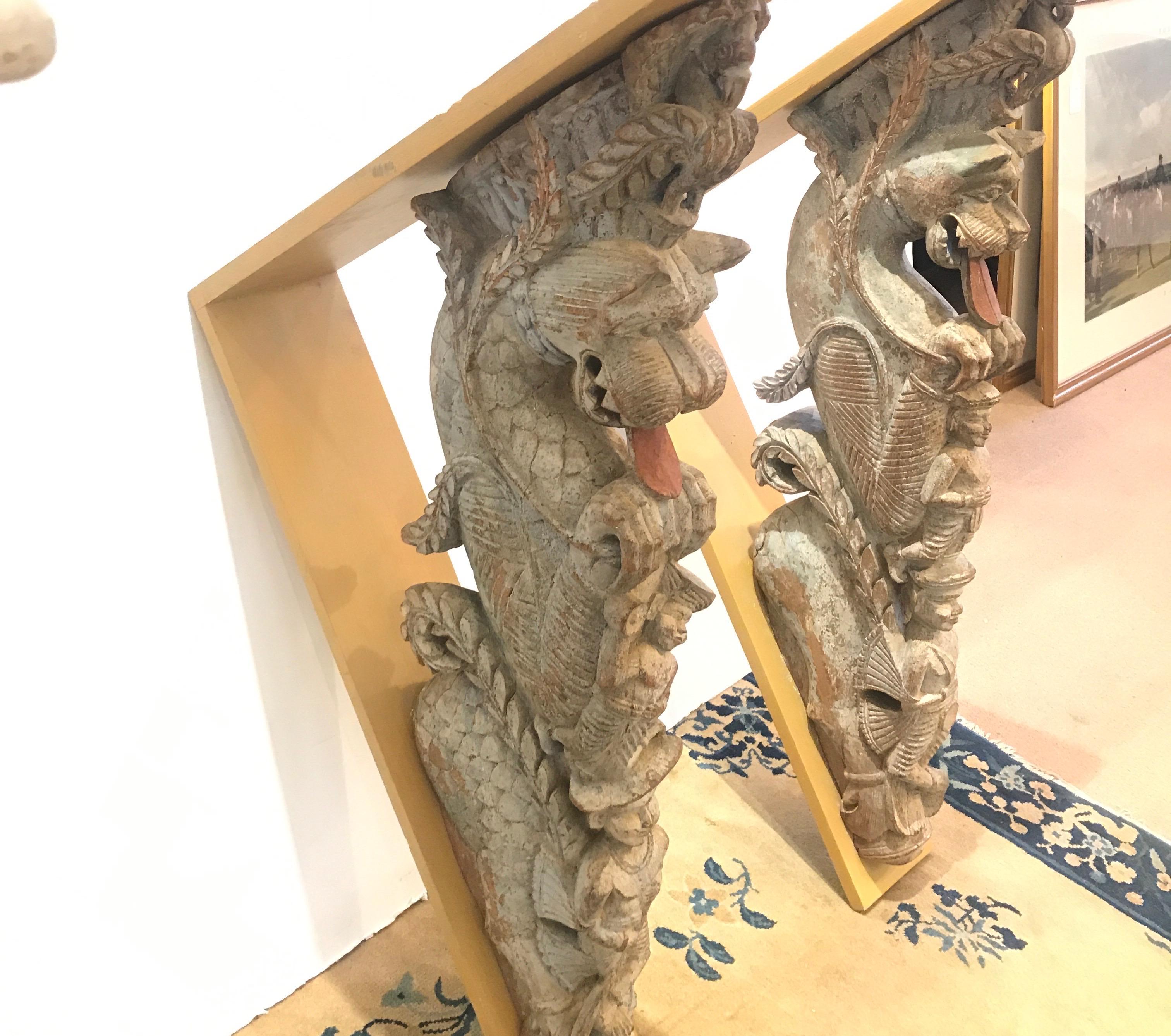 A pair of handcard hardwood architectural temple caved brackets. These carvings with some aged original paint possibly from Bali. 32 inches tall,. 24.5 inched deep inclining the support brackets.